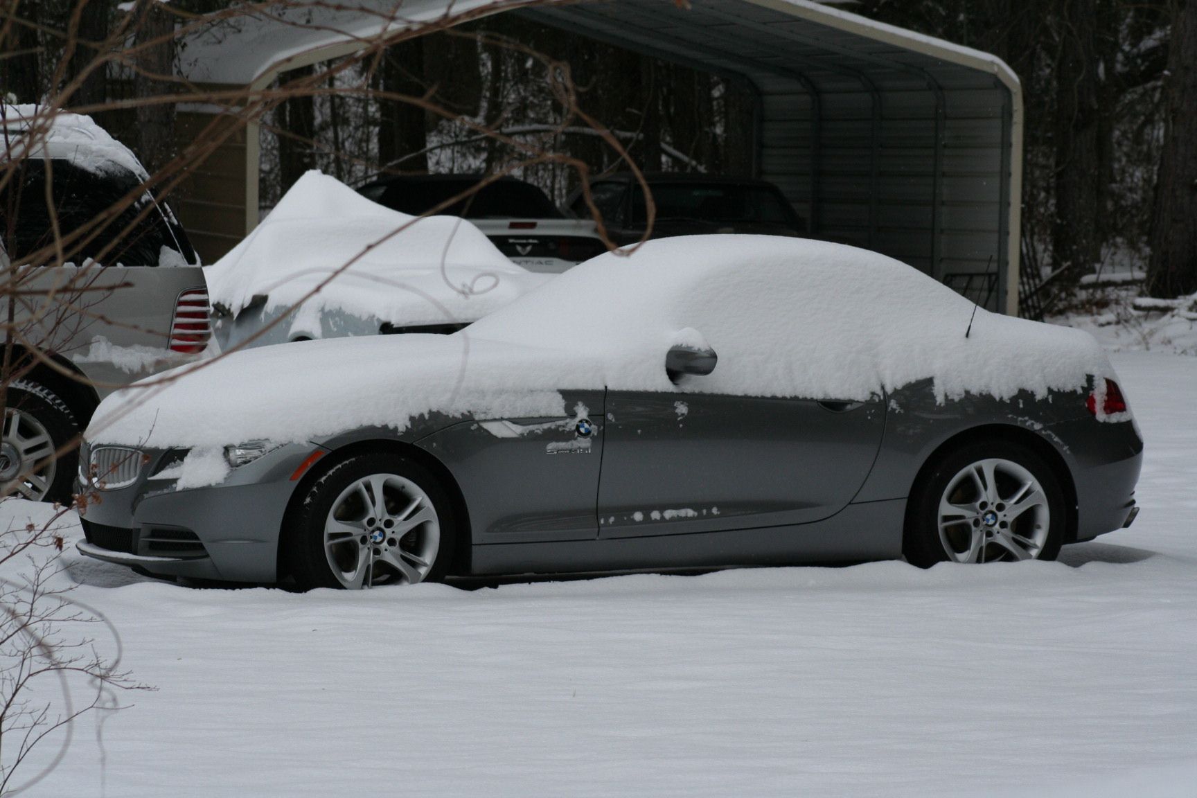 A snow-covered BMW Z4 parked in a snowy driveway