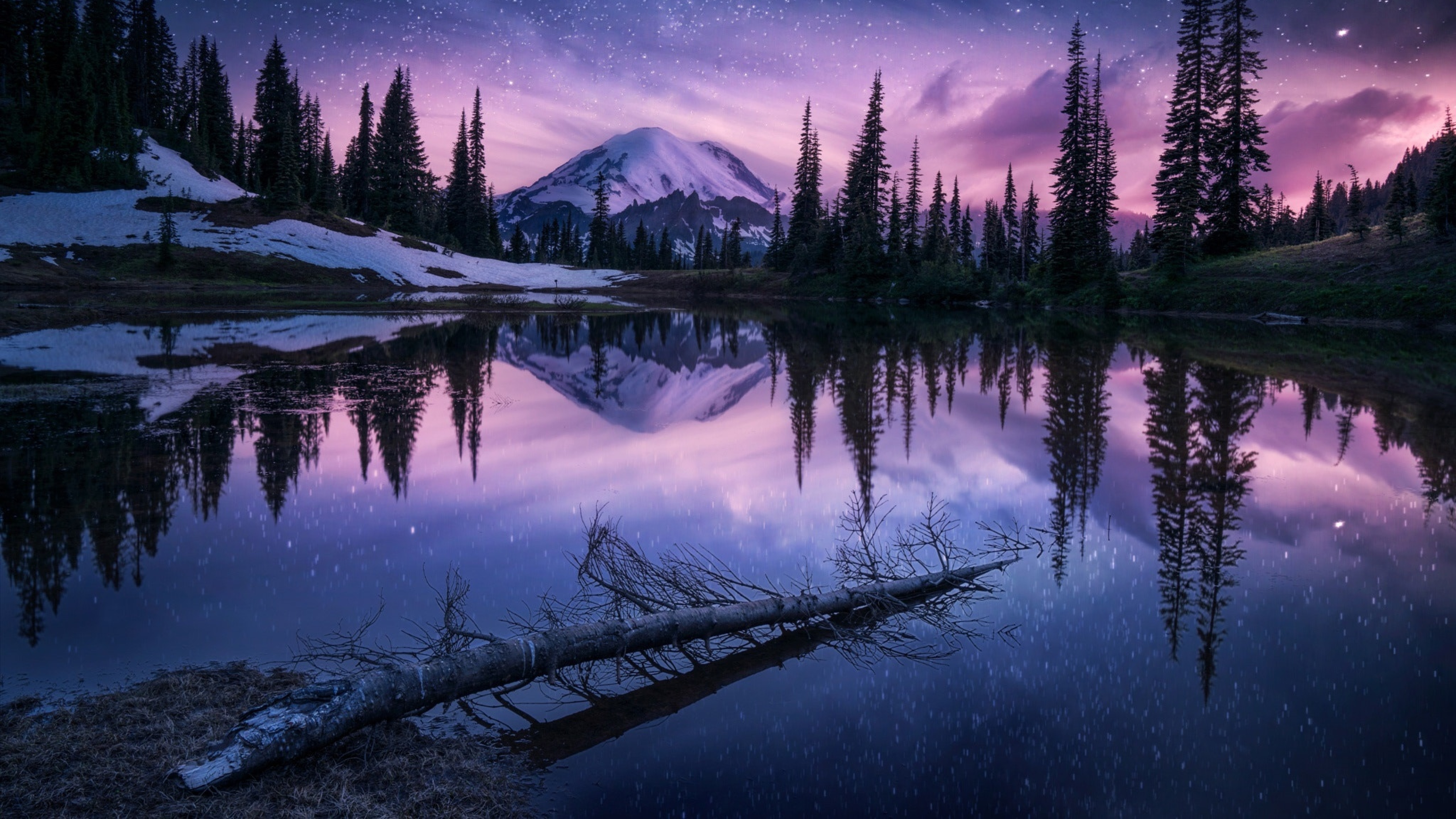 A stunning 4K scenery wallpaper showcasing a tranquil lake reflecting a majestic snow-capped mountain under a vibrant starry night sky