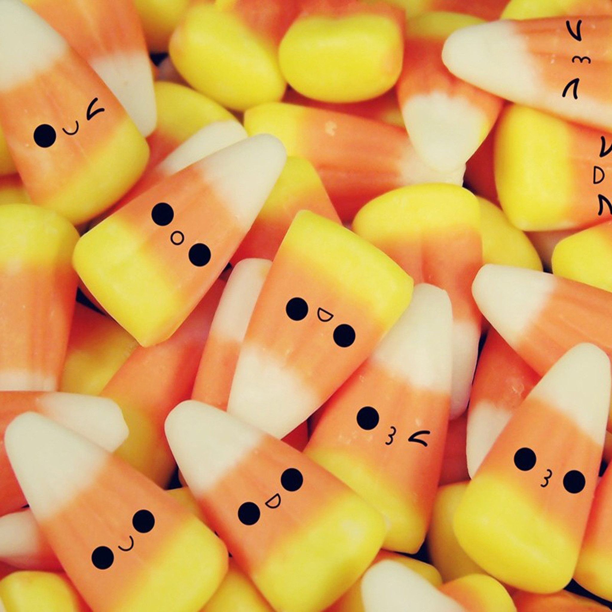 Close-up of candy corn pieces with cute kawaii faces, perfect for a cheerful laptop wallpaper