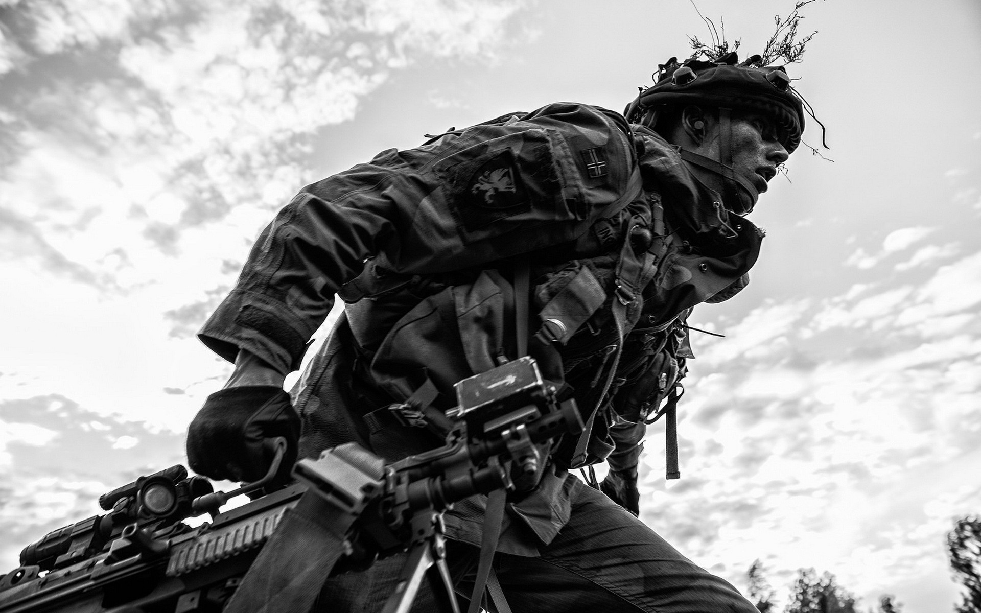 A German soldier advances with a machine gun under a cloudy sky