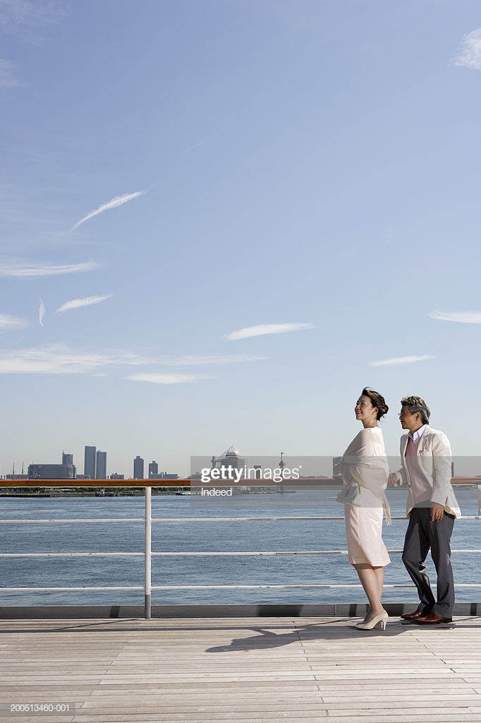 Mature Couple On Deck Of Cruise Ship Skyline In Background Side