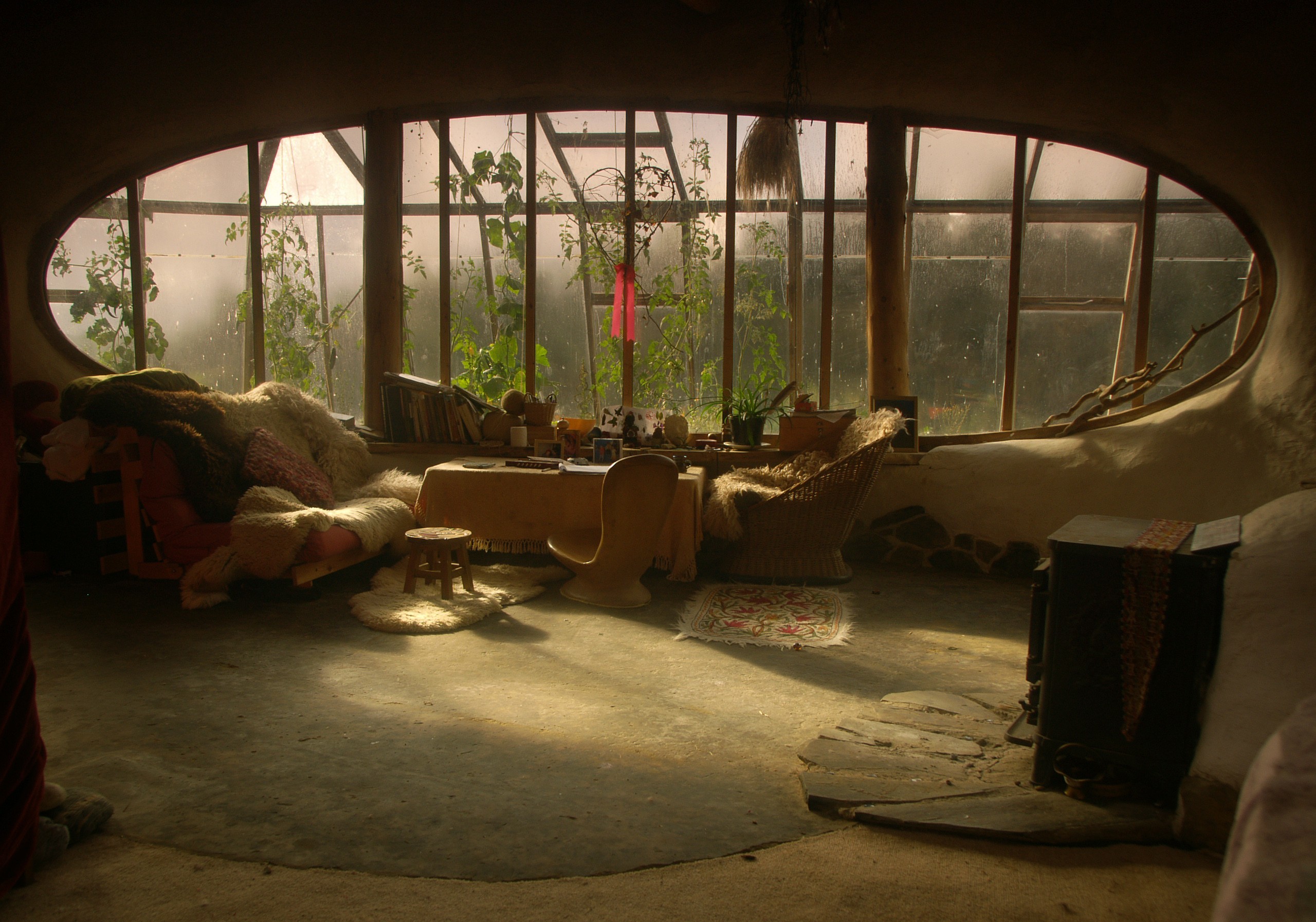 Cozy rustic interior with a large oval window overlooking a misty landscape