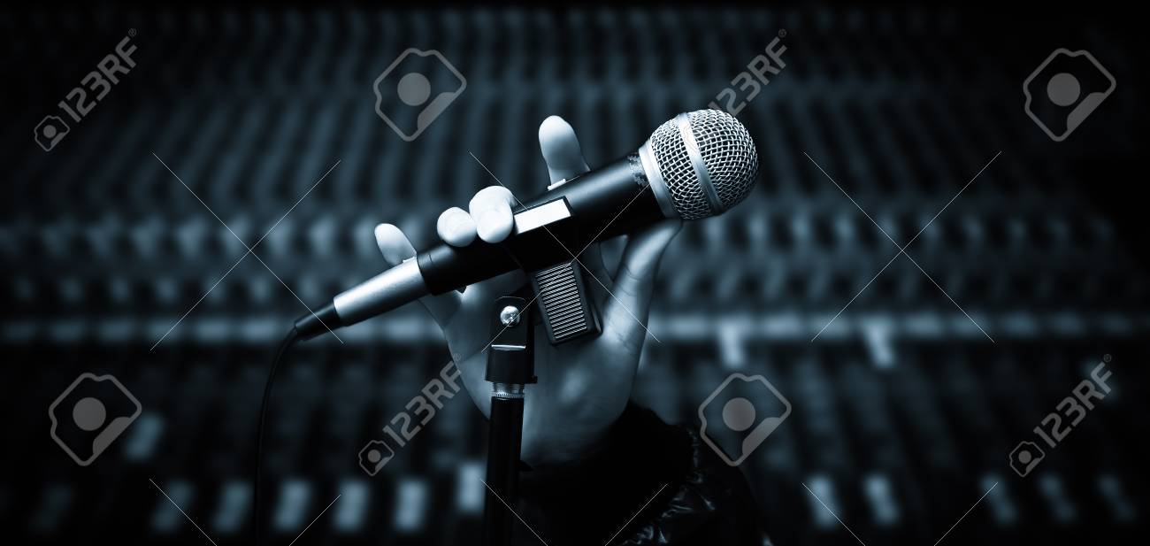 Singer Hands Holding Microphone On Studio Mixer Background