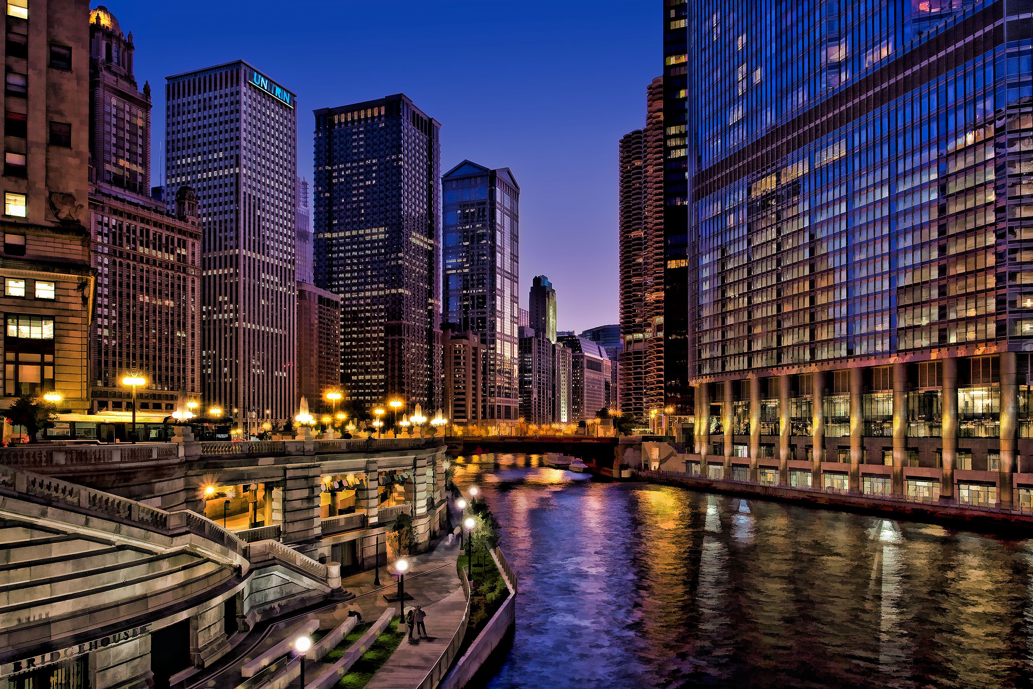 A breathtaking view of the Chicago skyline at dusk, with the Chicago River reflecting the city lights. Skyscrapers and urban architecture line the riverbanks, creating a stunning cityscape