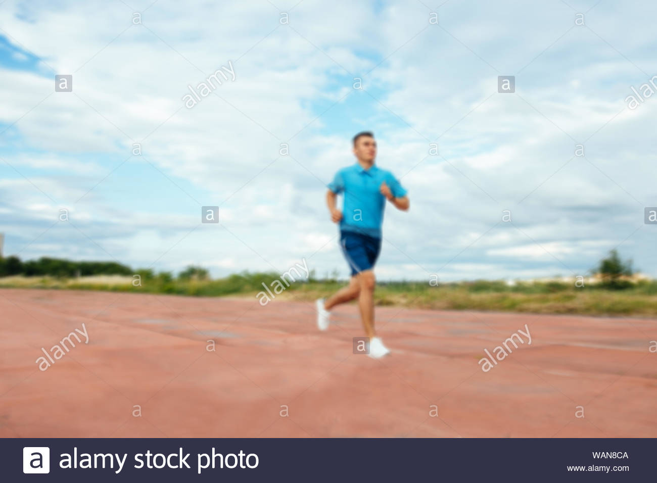 Young Handsome Active Sportsman Running On Track Field Blurred