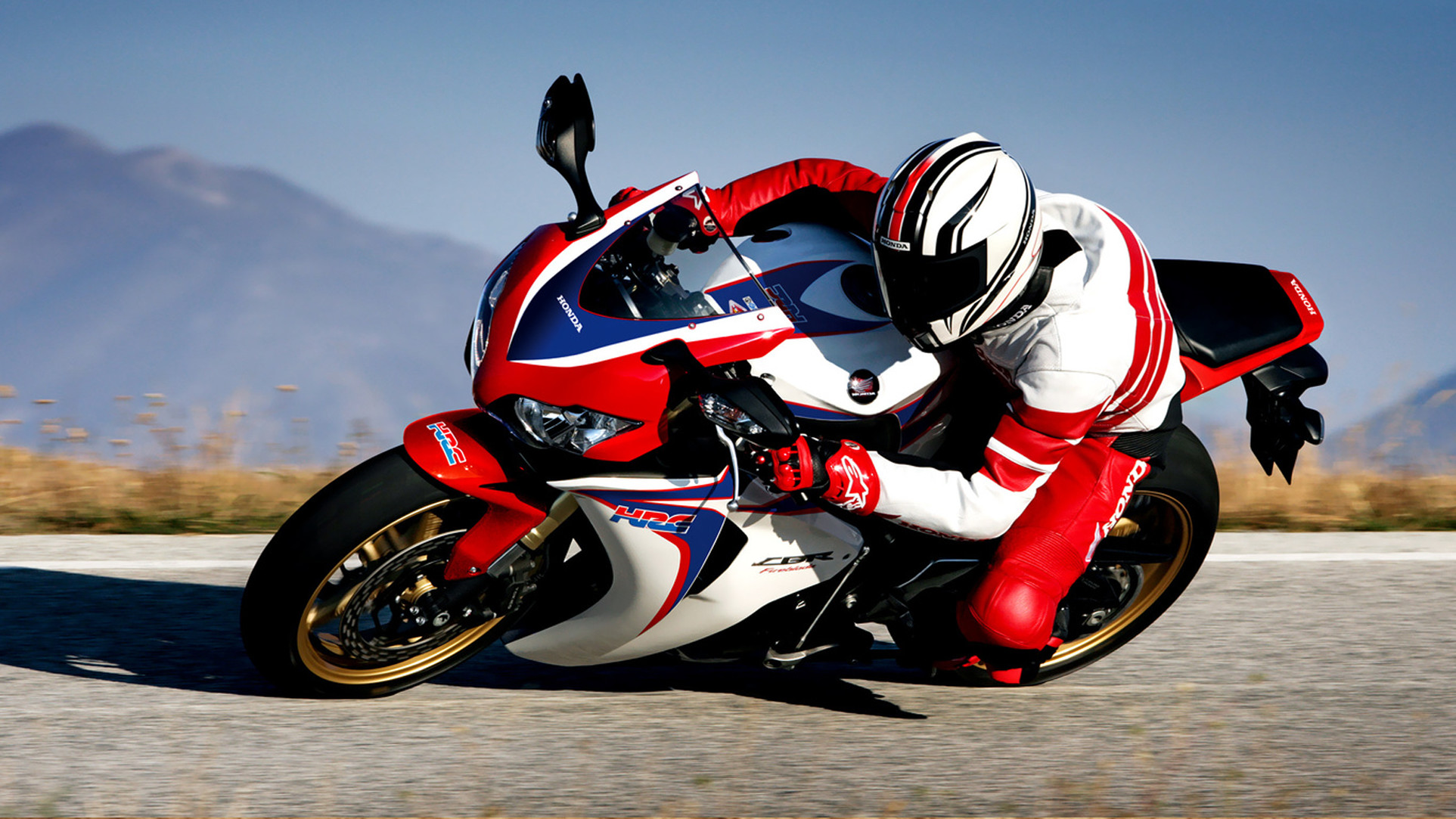 A Honda CBR1000RR Fireblade sportbike leaning into a turn on a scenic mountain road