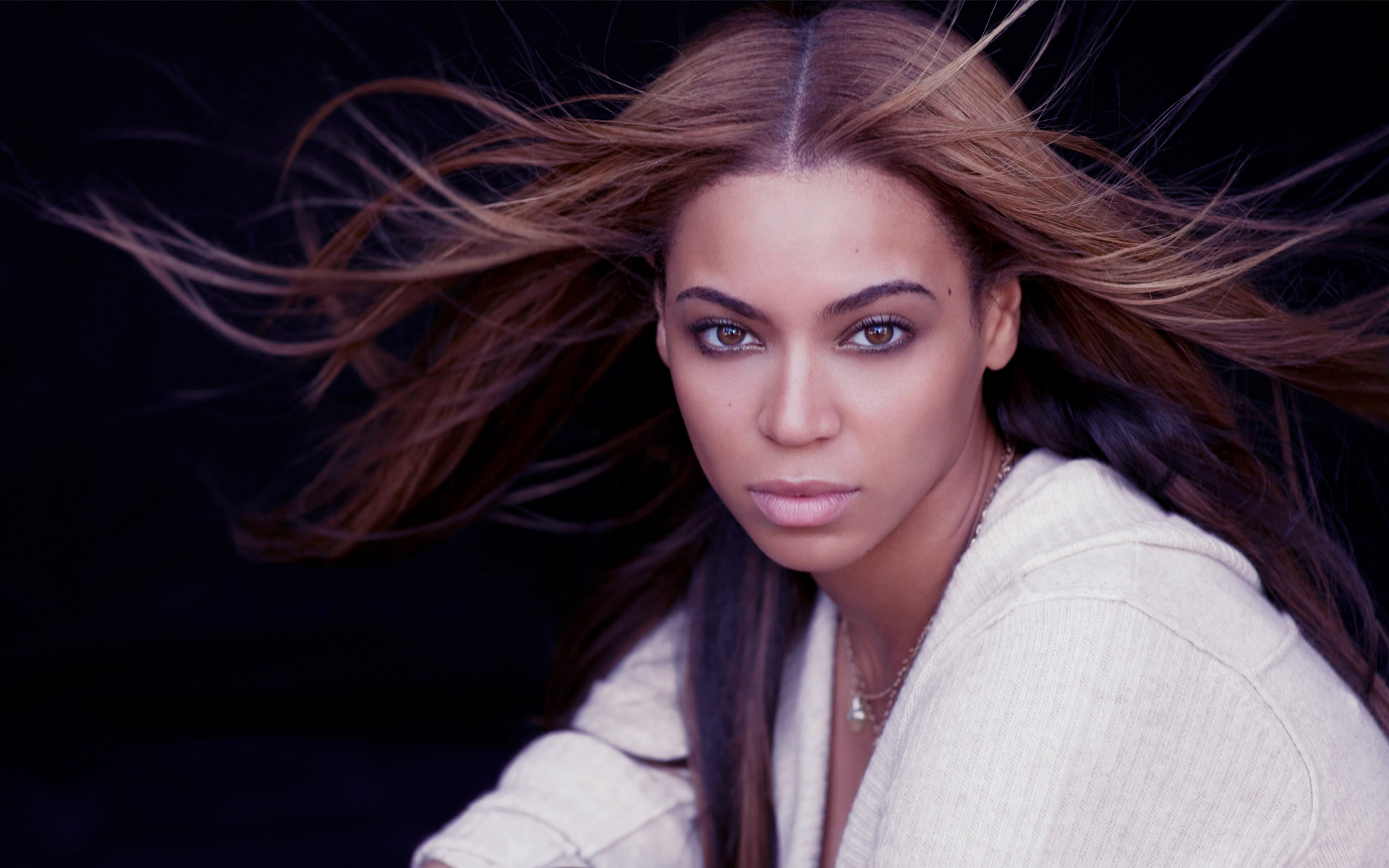 Beyoncé Knowles-Carter with windswept hair against a dark background