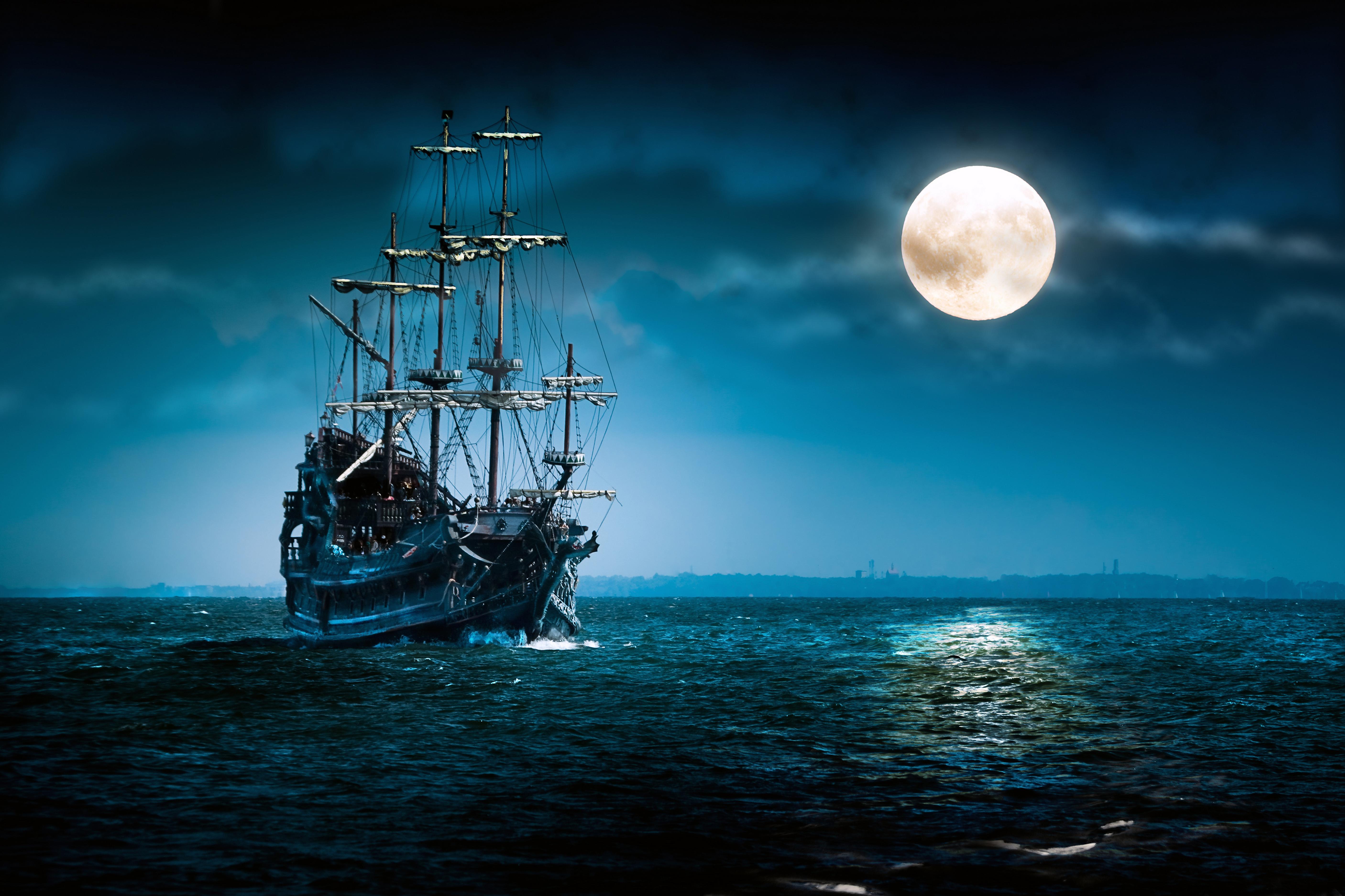 One beautiful pirate ship sailing in blue ocean by the bright full