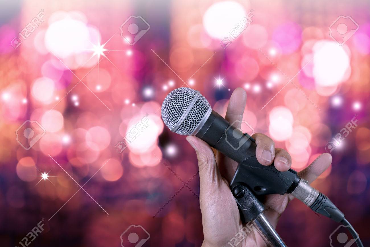 Hand Holding Microphone On Stand With Bokeh Glow Blurred