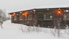 Exterior Of A Log Cabin In Snowstorm With Weling Glowing Orange