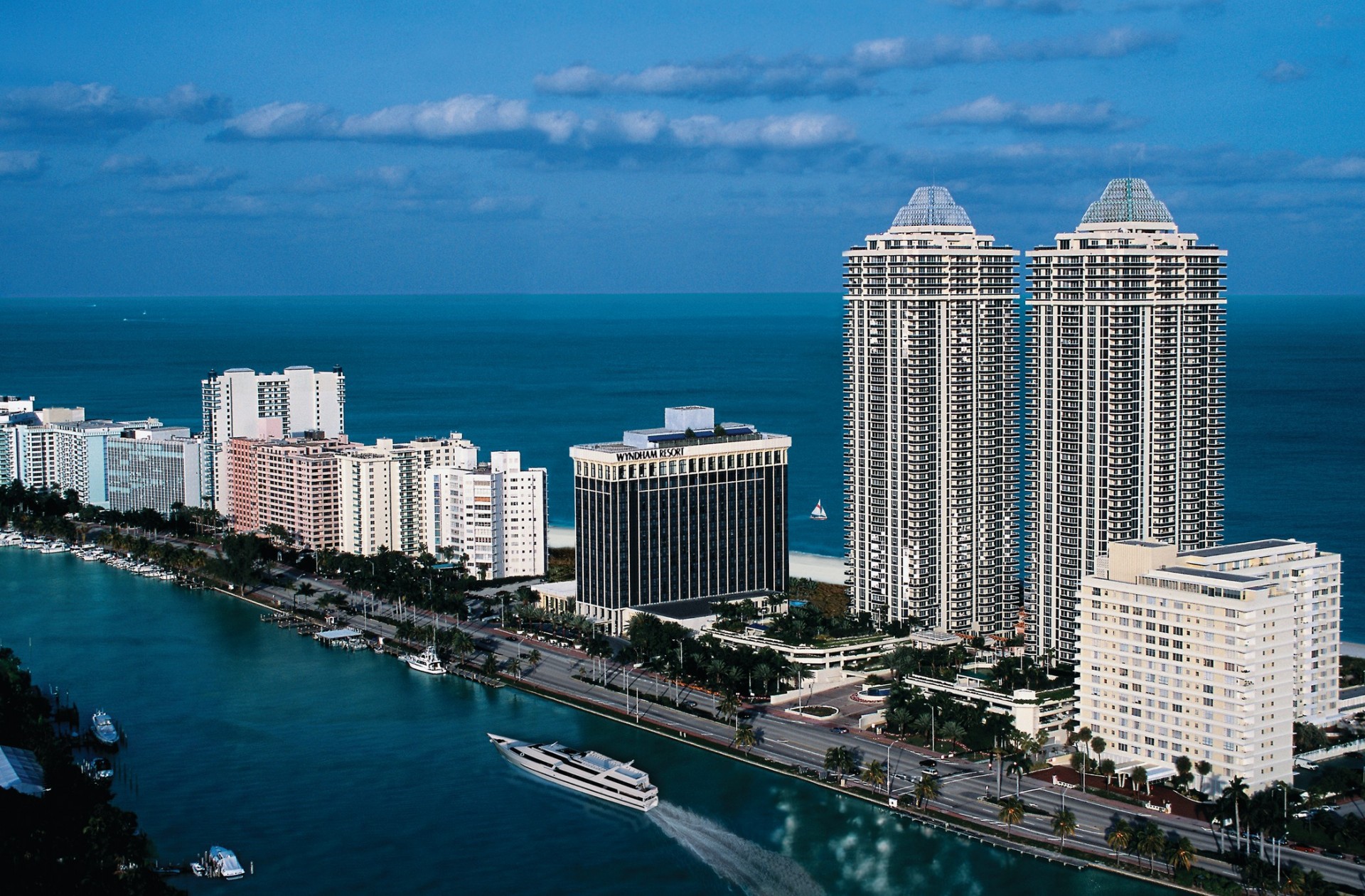 Aerial view of Miami Beach skyline with luxury hotels, turquoise ocean, and boats