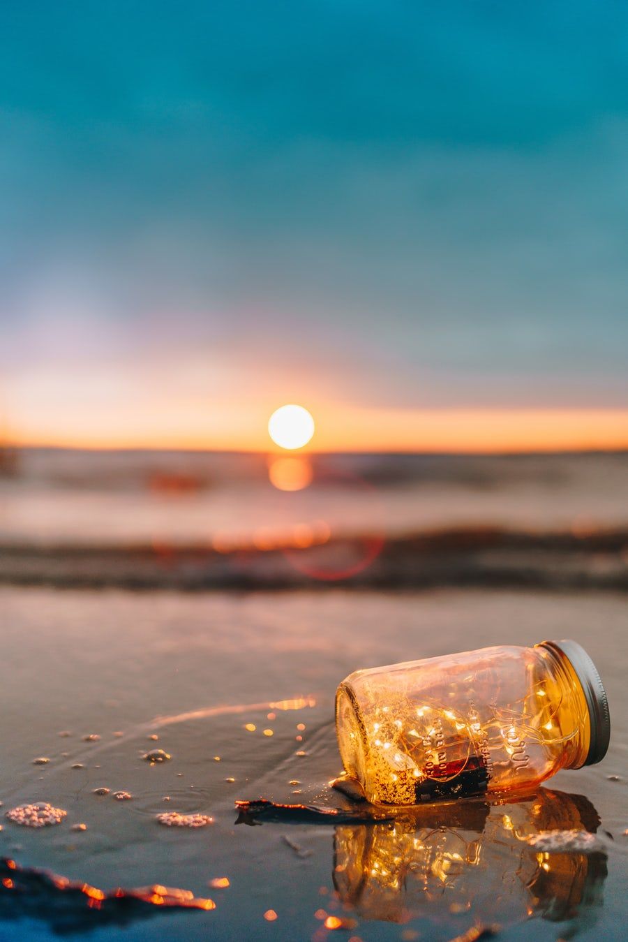 Clear Glass Mason Jar On Beach During Sunset Lit Wallpaper