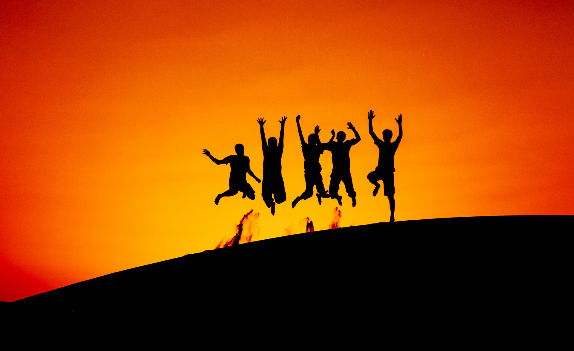 Silhouettes of five friends jumping in celebration against a vibrant sunset, symbolizing joy, freedom, and the bonds of friendship