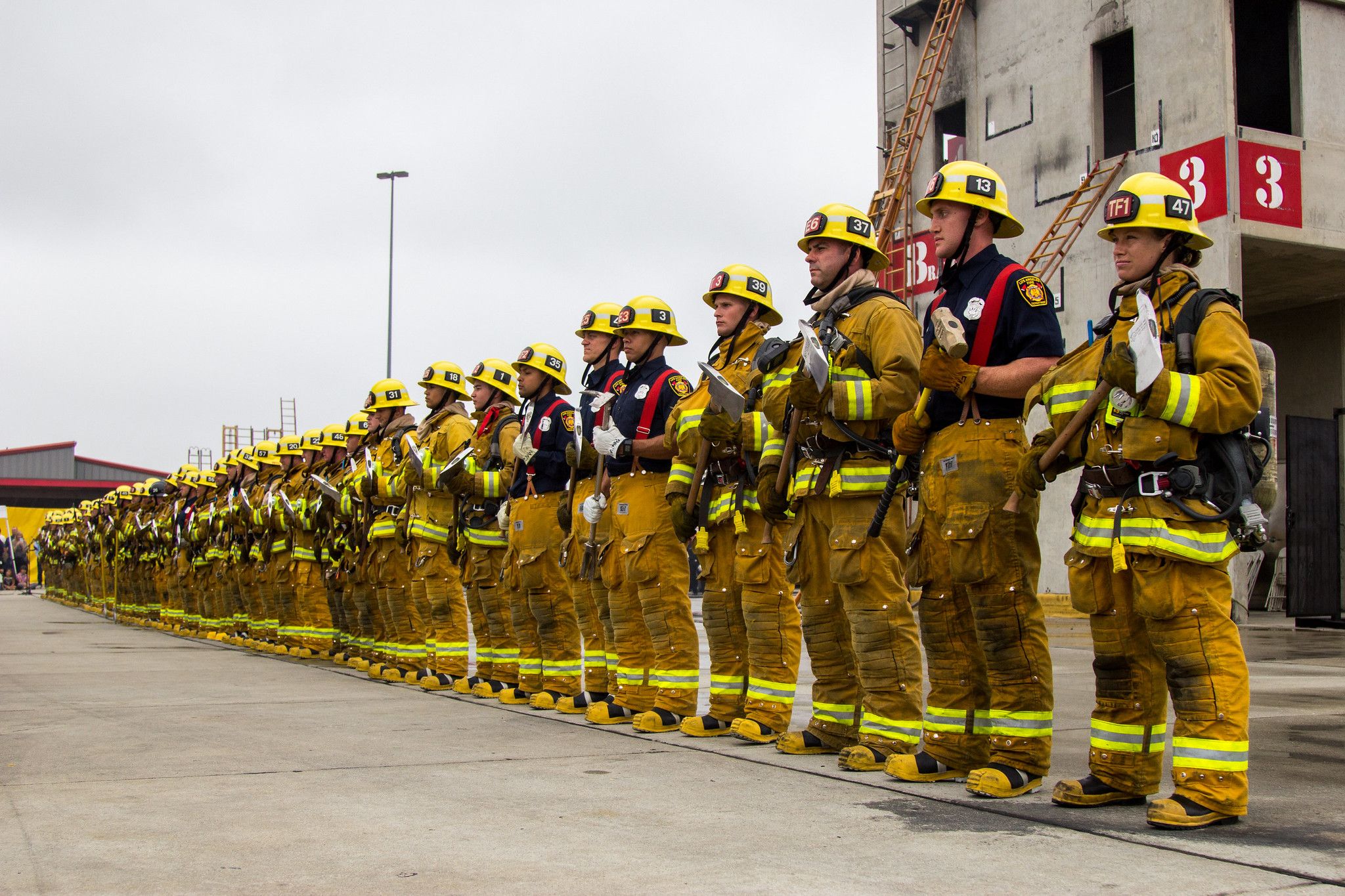 A line of Los Angeles Fire Department (LAFD) firefighters stand at attention, possibly during a graduation ceremony or training exercise