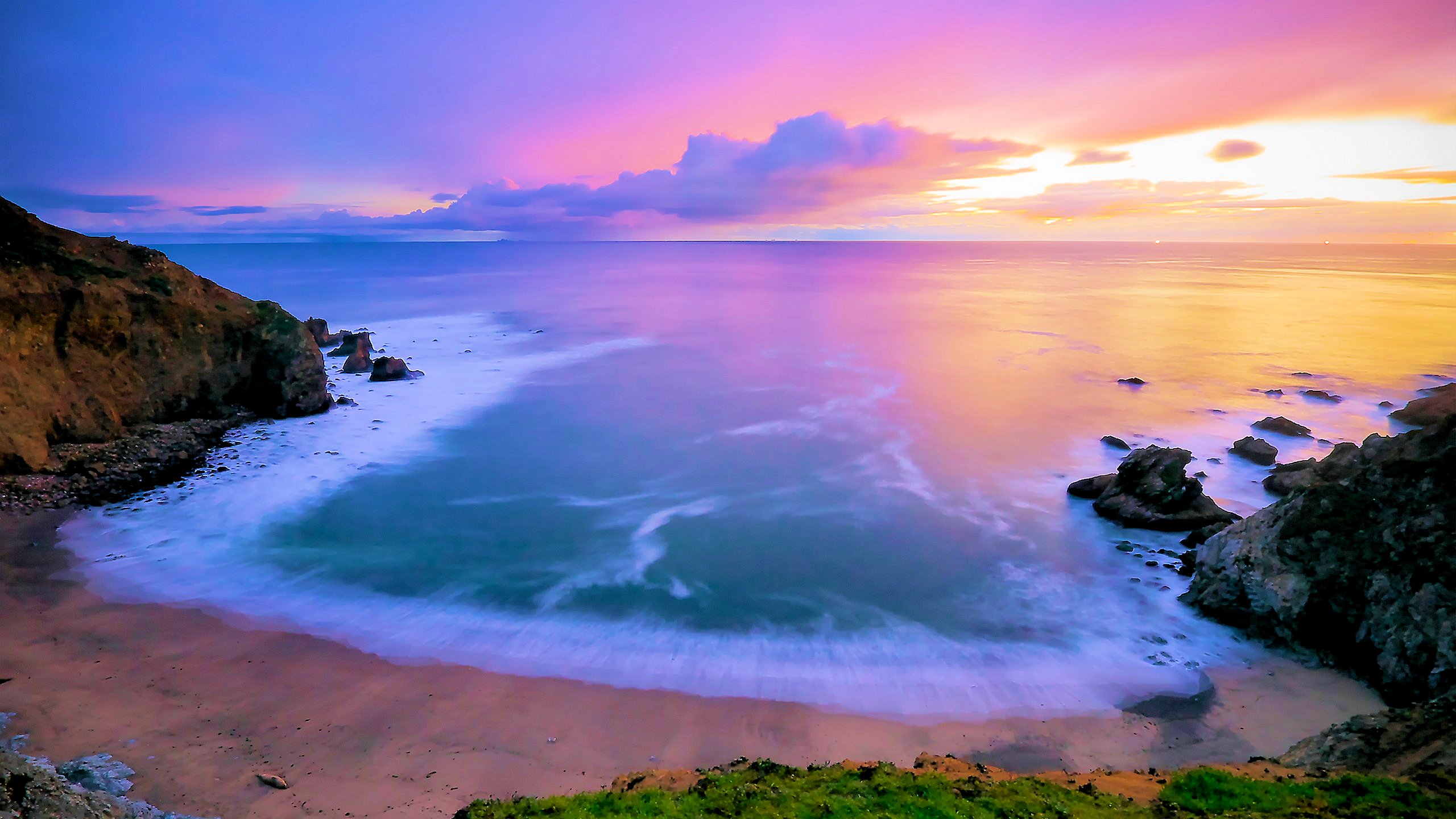 A breathtaking sunset over a secluded beach cove, with vibrant colors painting the sky and the smooth, wave-kissed sand