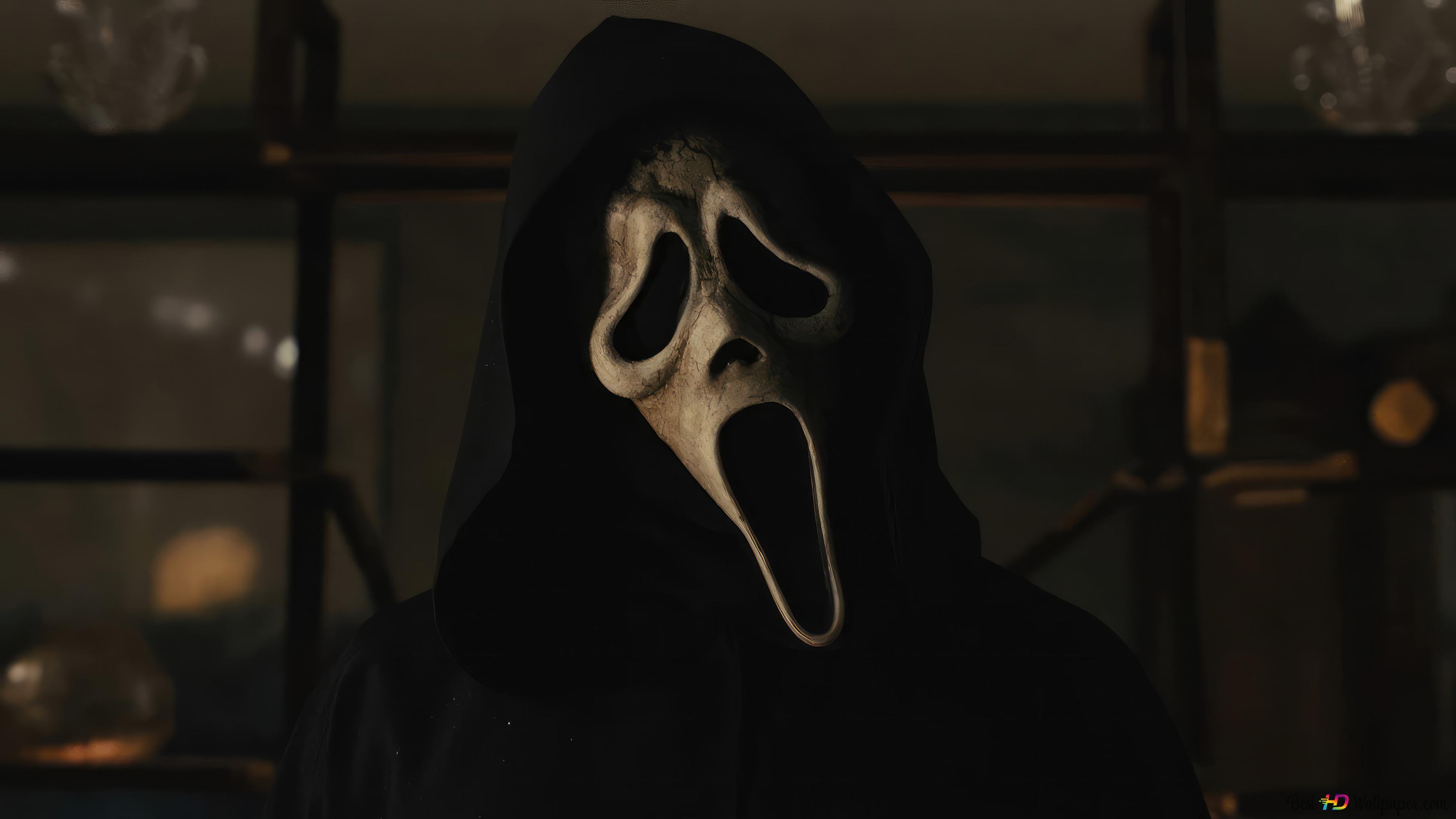 Ghostface, the masked killer from the Scream movie franchise, stands ominously in a dimly lit room, likely from one of the later films in the series. His signature mask is highlighted against the dark background, enhancing the suspenseful and horror-filled atmosphere