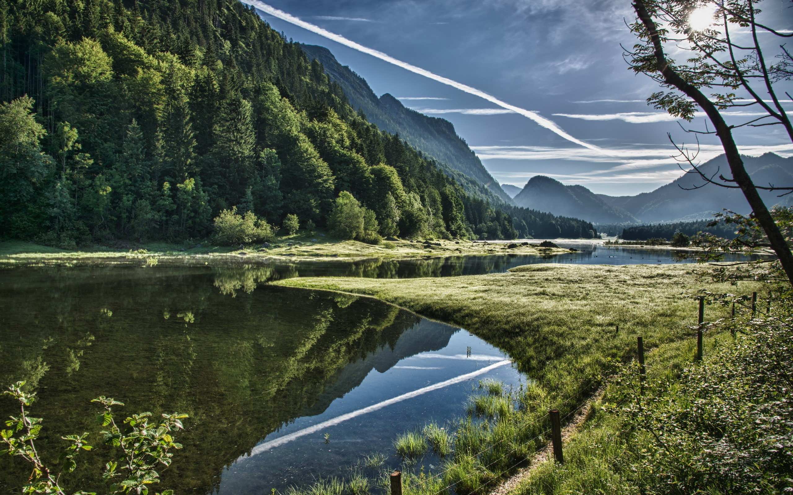 Serene 4K landscape with a pristine lake reflecting the sky and a lush green forest