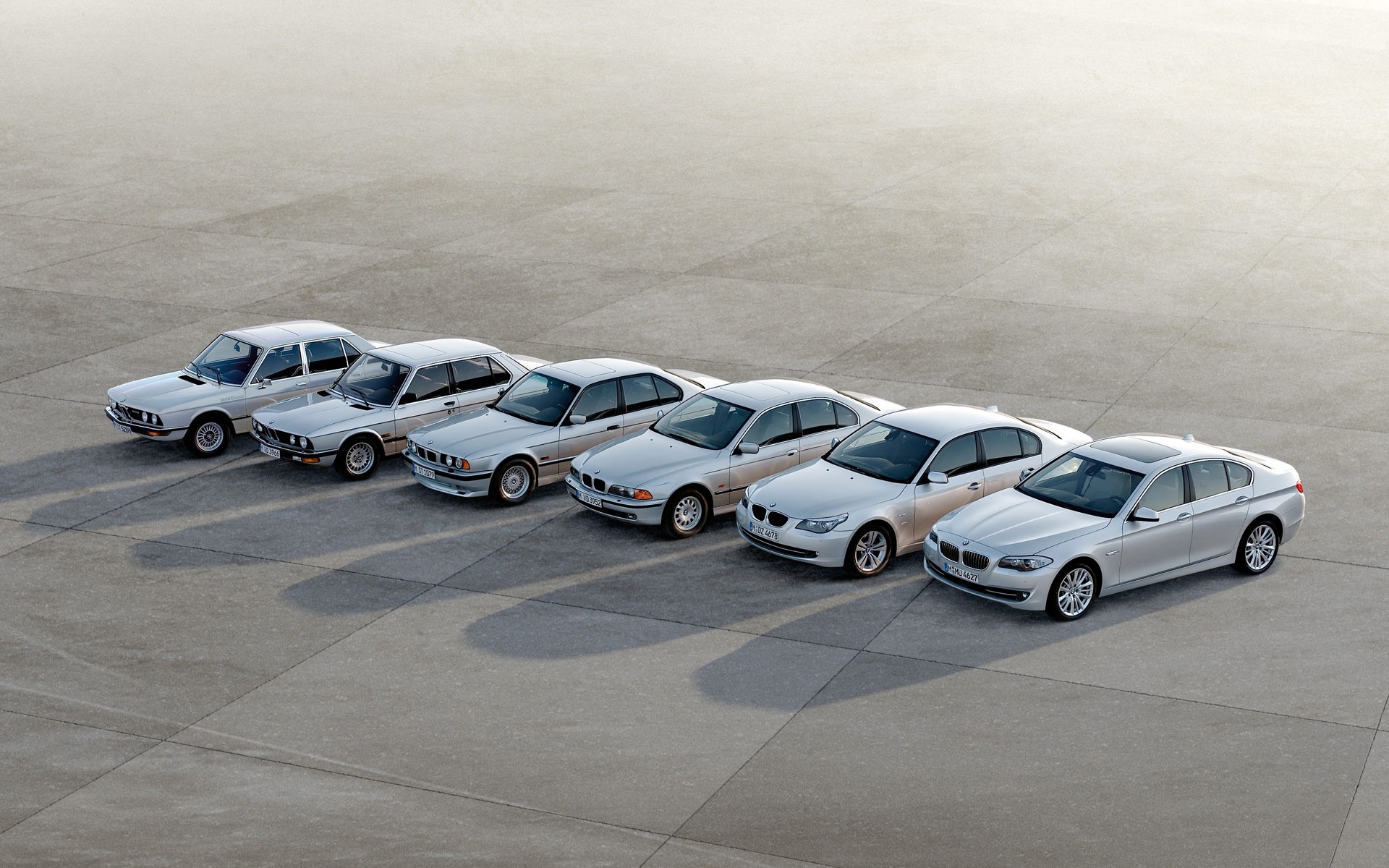 Six Generations of BMW 5 Series lined up on a concrete surface