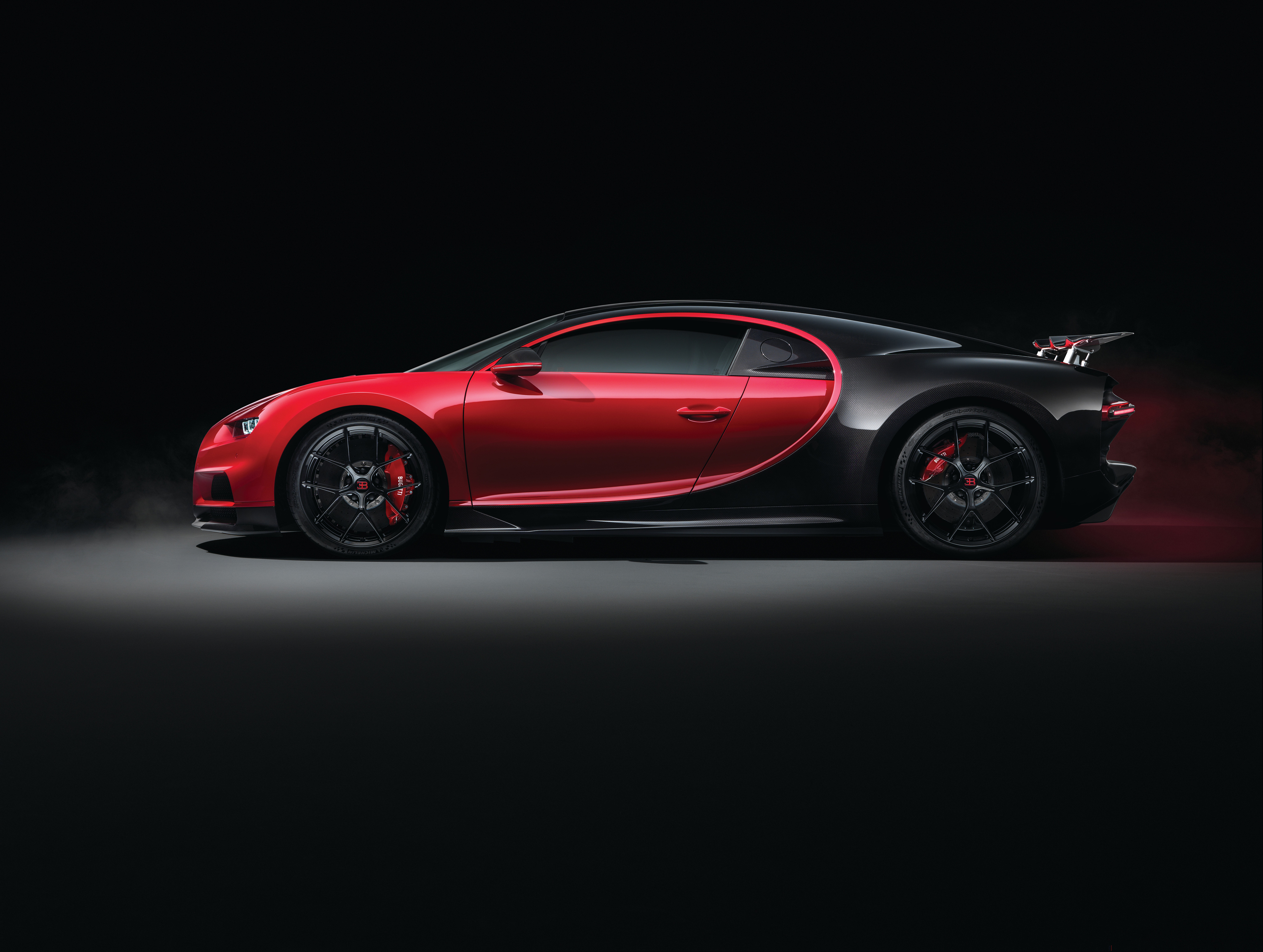 A side view of a red and black Bugatti Chiron Super Sport, highlighting its sleek design and powerful presence