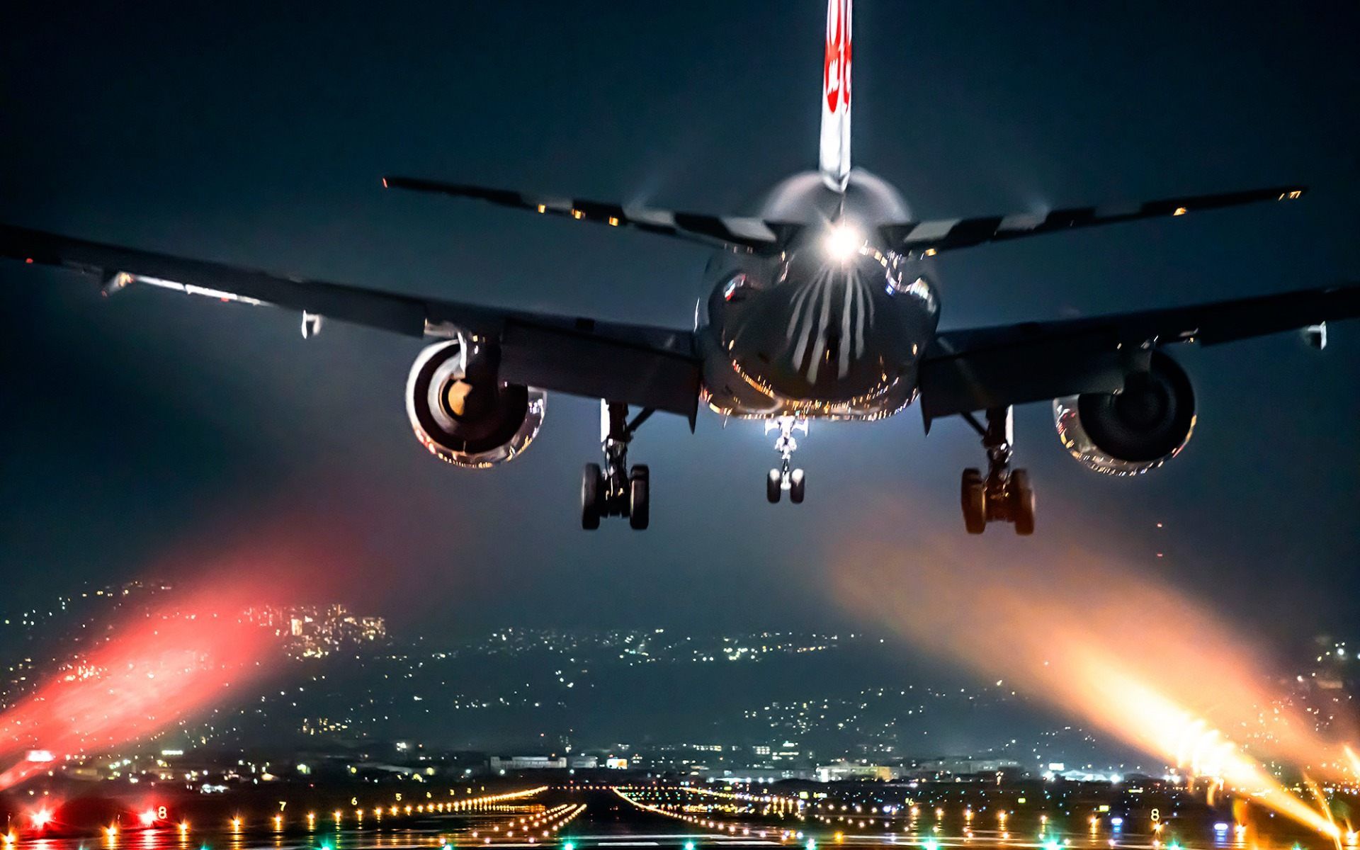 A passenger airplane landing at night on an airport runway, with city lights in the background