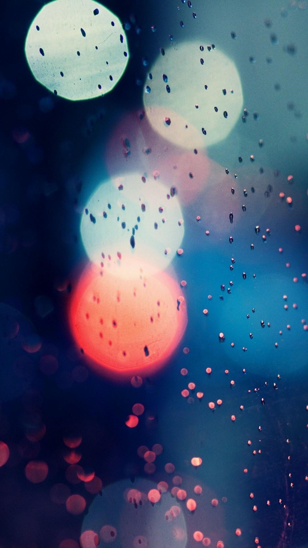 Abstract image of blurred city lights through a rain-speckled window, creating a cool and vibrant phone wallpaper
