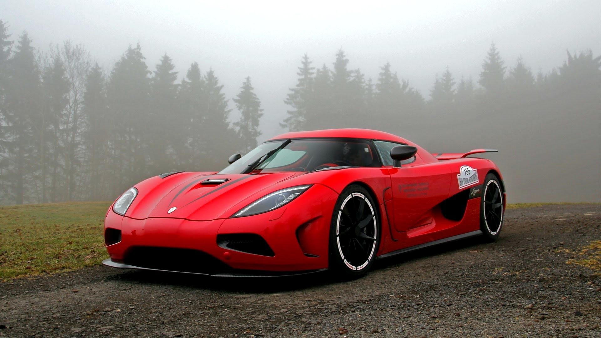 A vibrant red Koenigsegg Agera parked on a misty mountain road