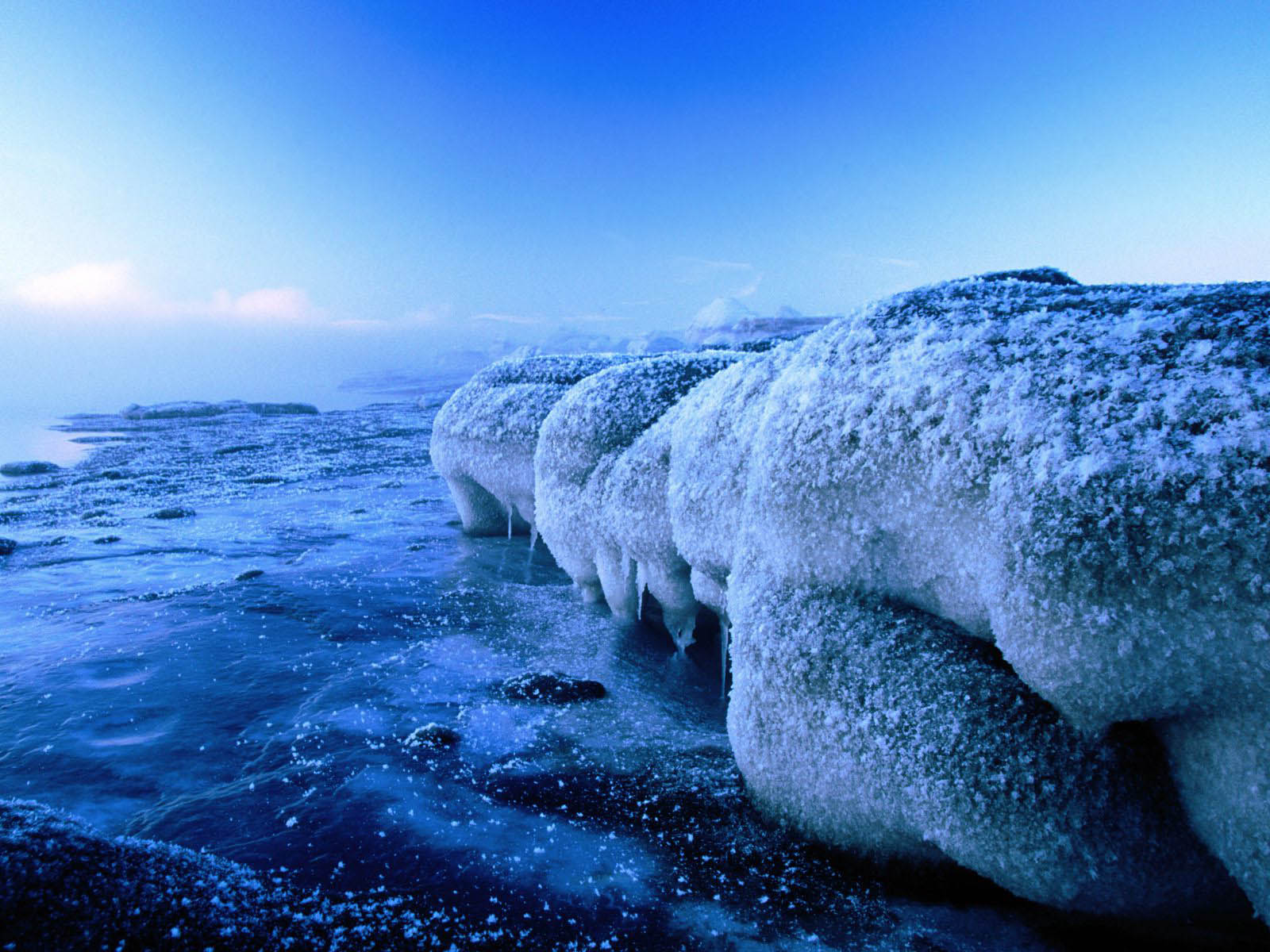 Ice-covered rocks on a frozen lakeshore during a frosty blue twilight