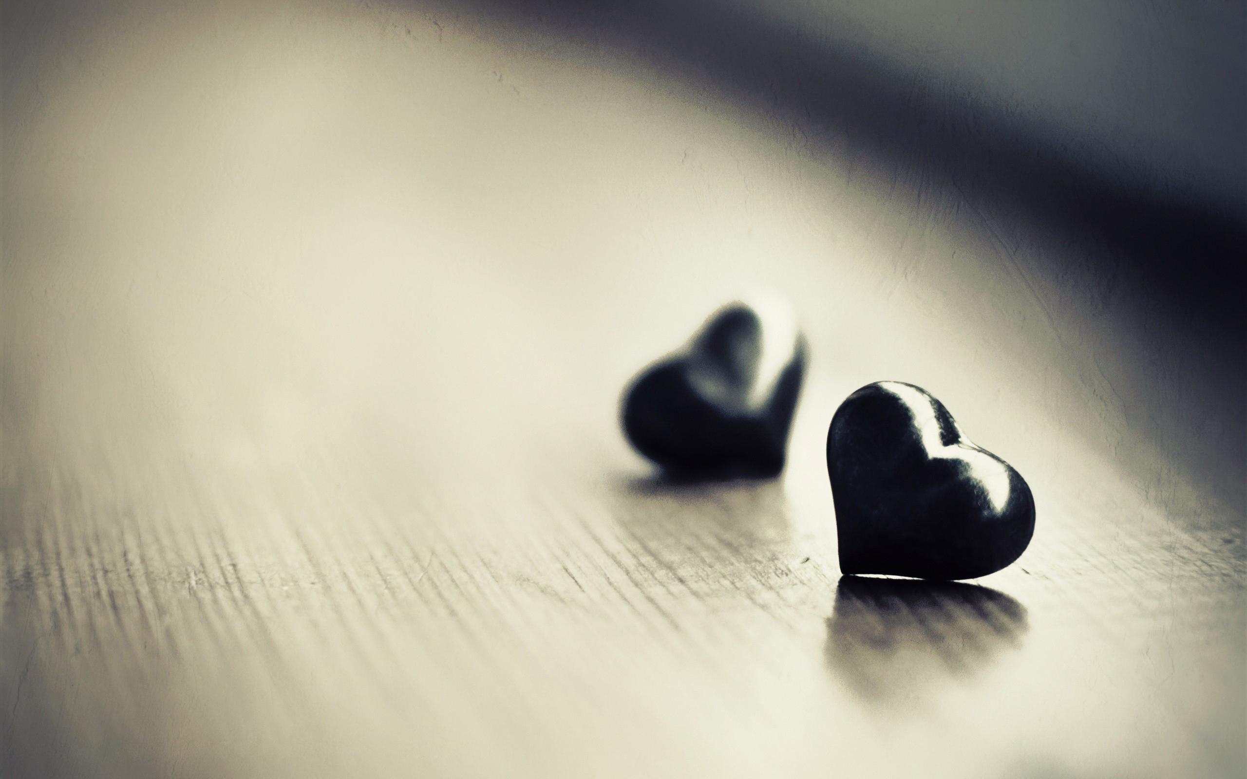 Two dark hearts resting on a wooden surface, symbolizing love and affection