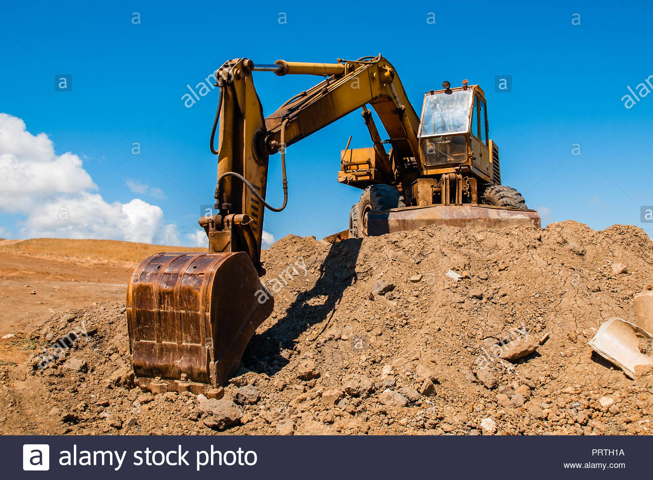 Excavator With Bucket Standing On Soil Hill And Blue Sky