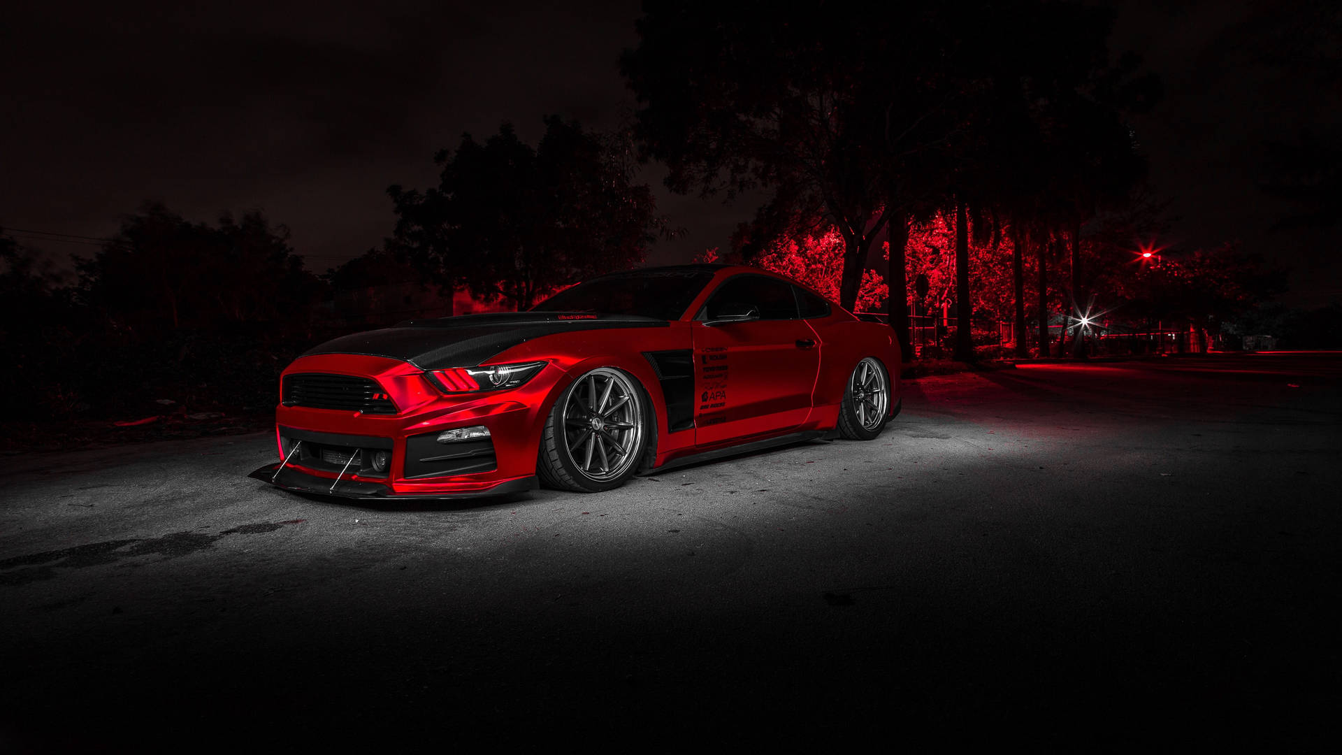 Red Ford Mustang parked on a dark street at night