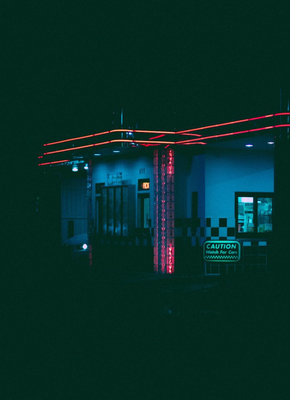 A gas station lit up at night with neon lights photo Free Neon