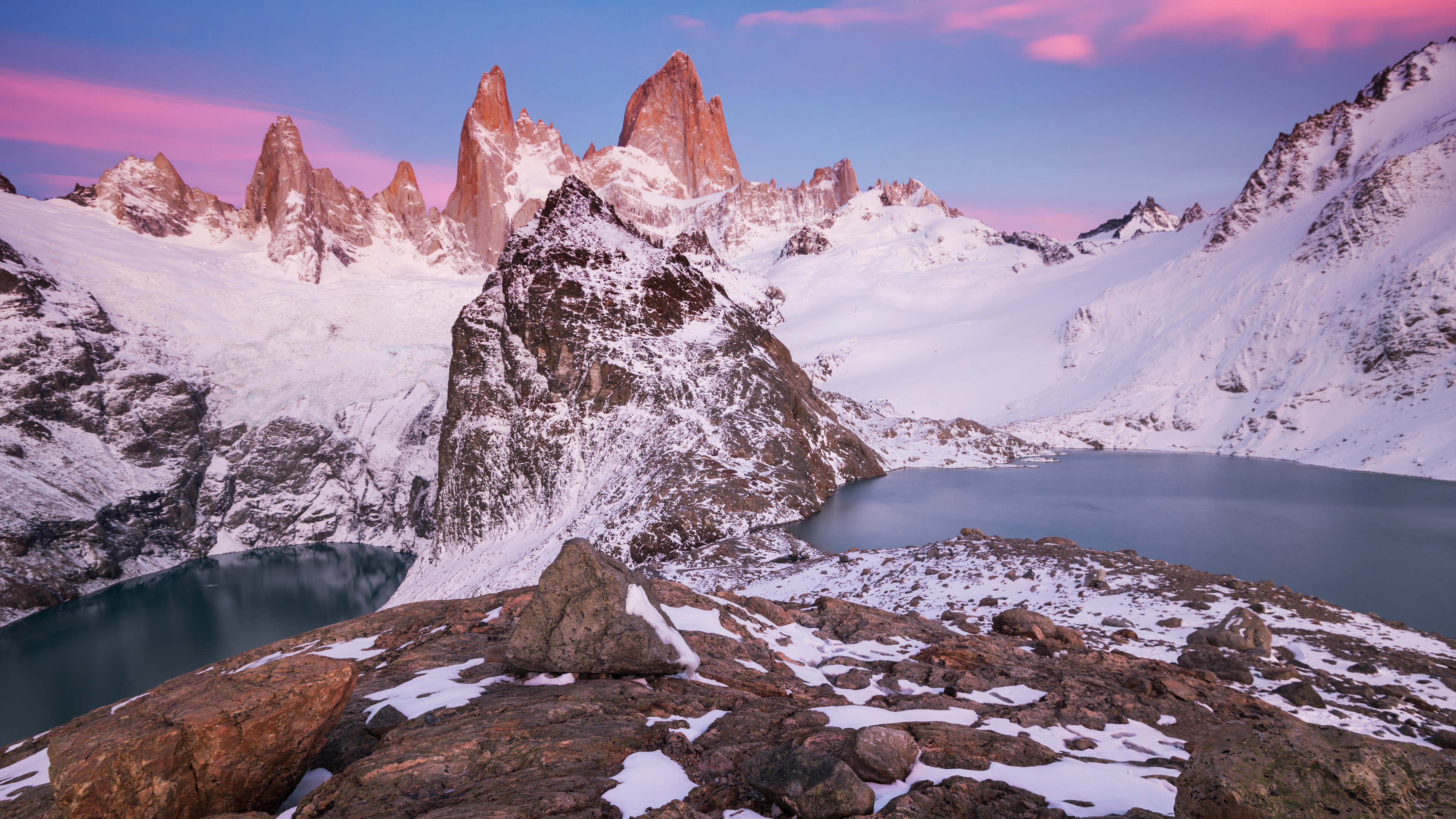 A breathtaking 4k wallpaper featuring a snow-covered mountain range at sunset, with a serene lake nestled in the foreground