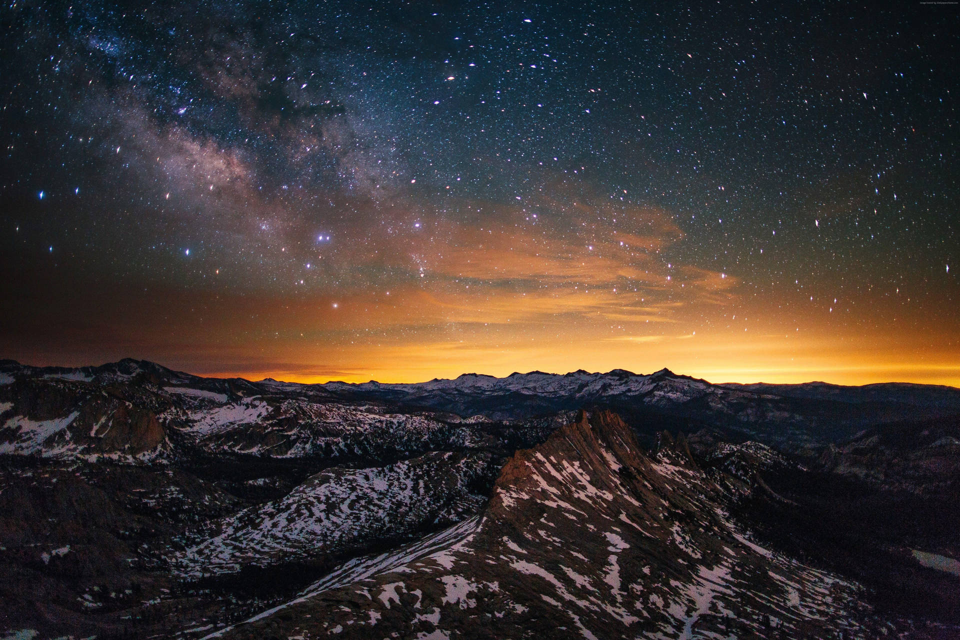 A breathtaking vista of snow-capped mountains under a vibrant, star-filled night sky