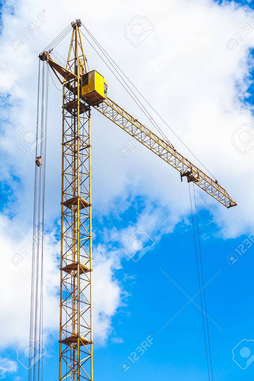 Yellow Hoisting Tower Crane On A Background Of Cloudy Sky