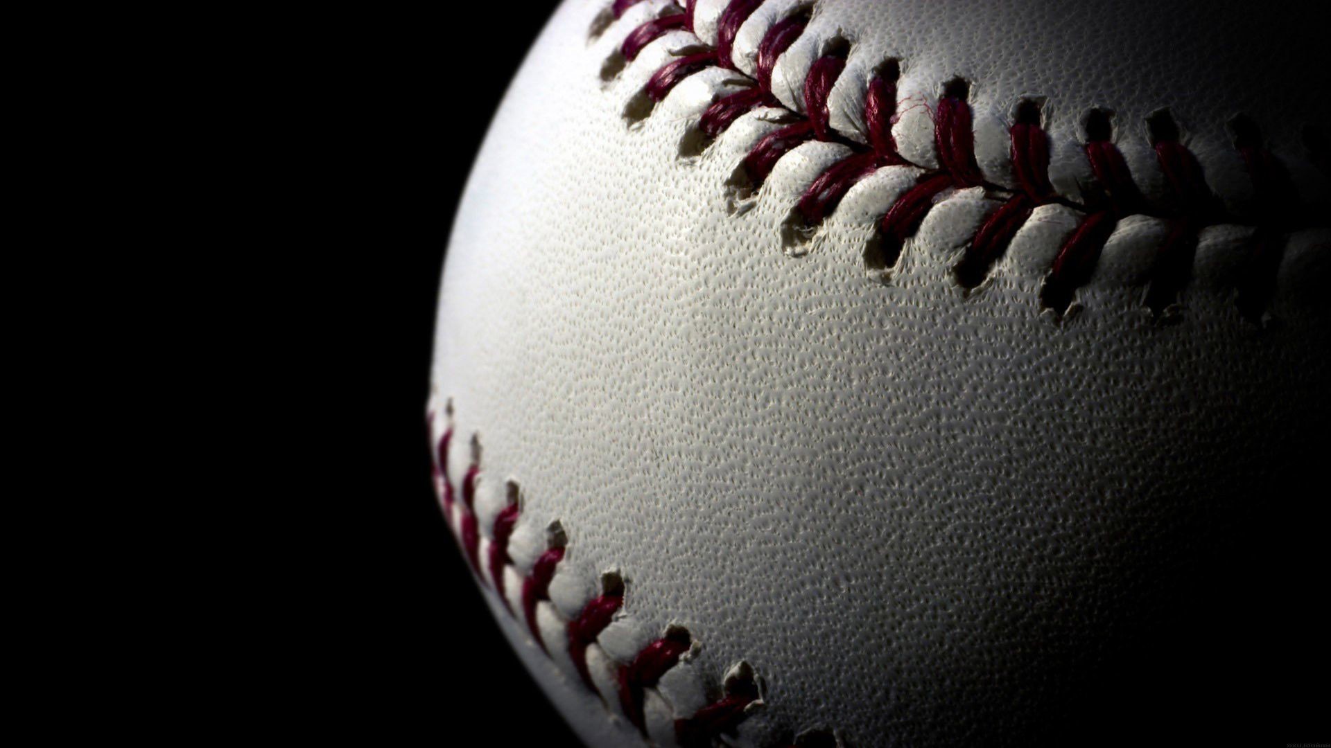 Close-up of a baseball against a dark background, highlighting the texture and stitching