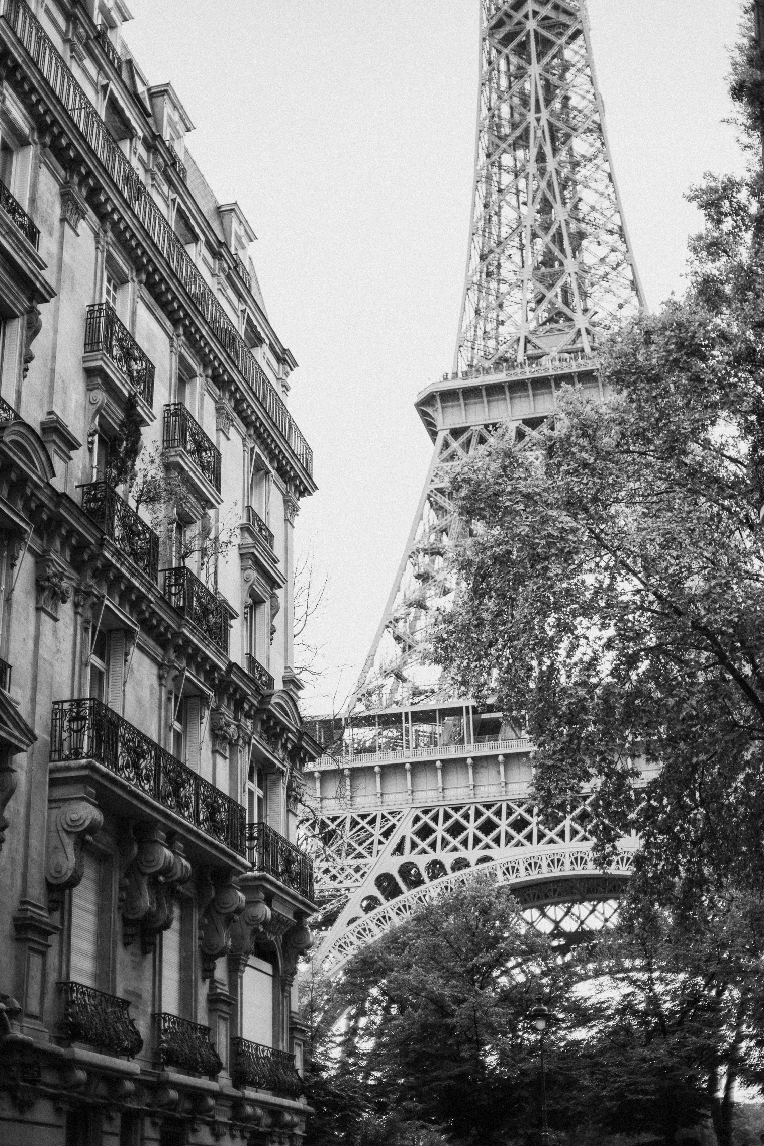 Black and white photo of the Eiffel Tower seen from a Parisian street