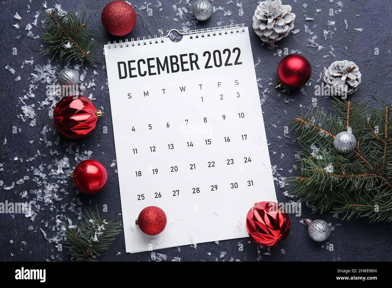 Paper calendar for December 2022 and Christmas decor on dark