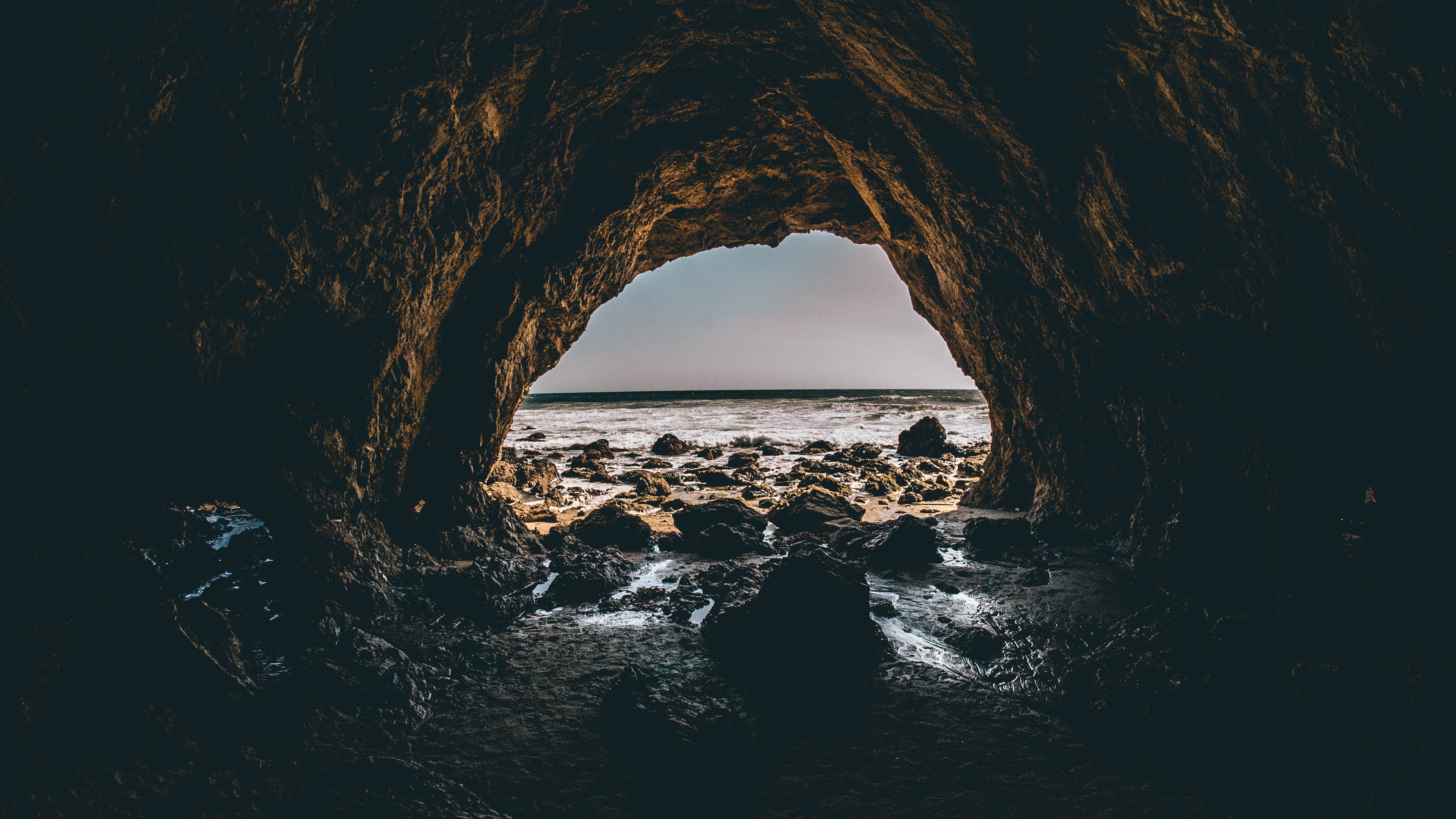 Dark sea cave opening to a rocky beach and ocean view