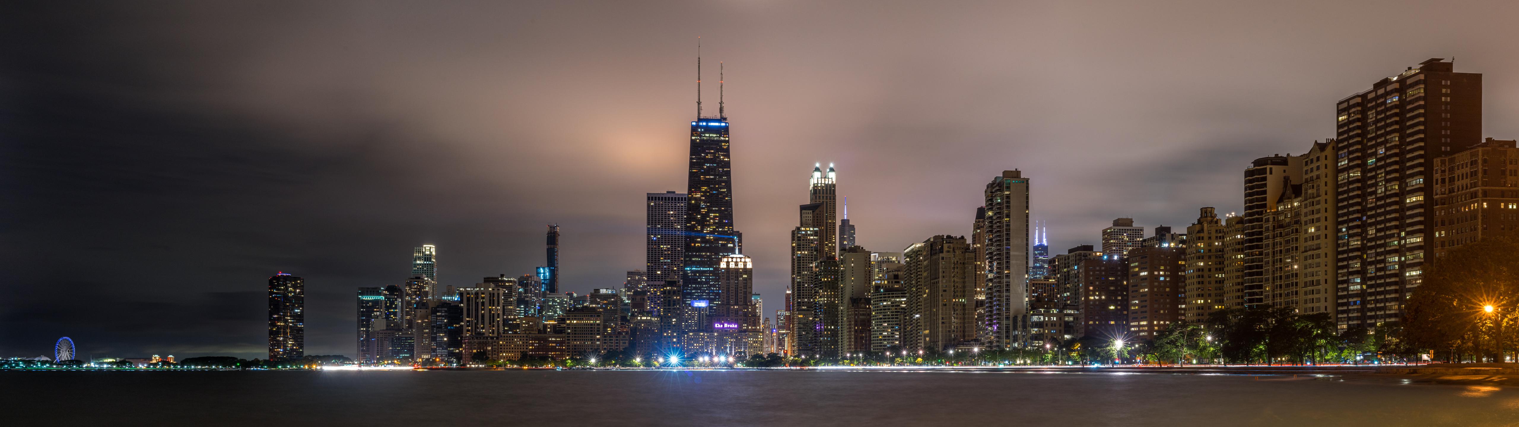 Chicago skyline at night with buildings lit up and reflecting in the water