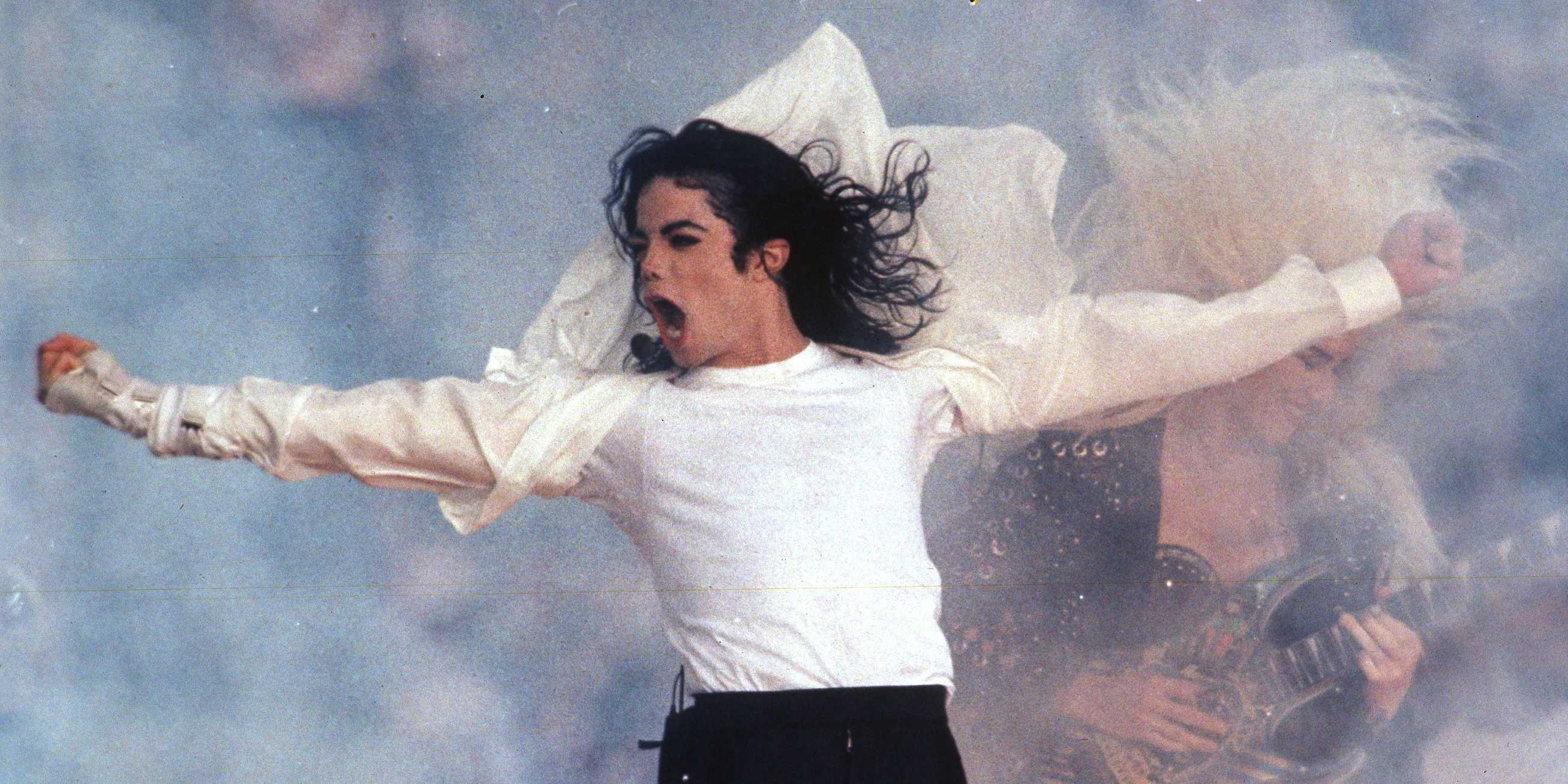 Michael Jackson performing on stage with a guitarist in the background