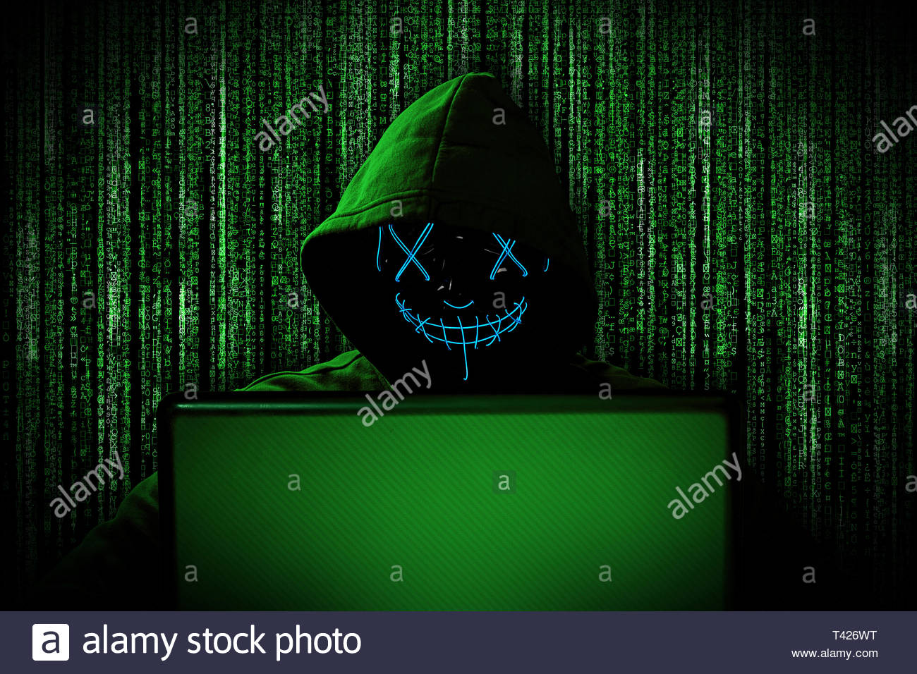 Hacker With Glowing Mask Behind Notebook Laptop In Front Of Green