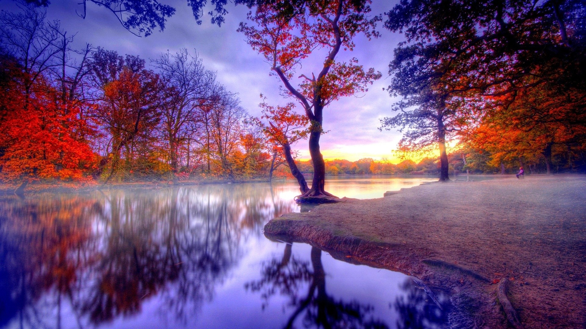 A serene autumn landscape with a tranquil lake reflecting the colorful foliage and a vibrant sunset