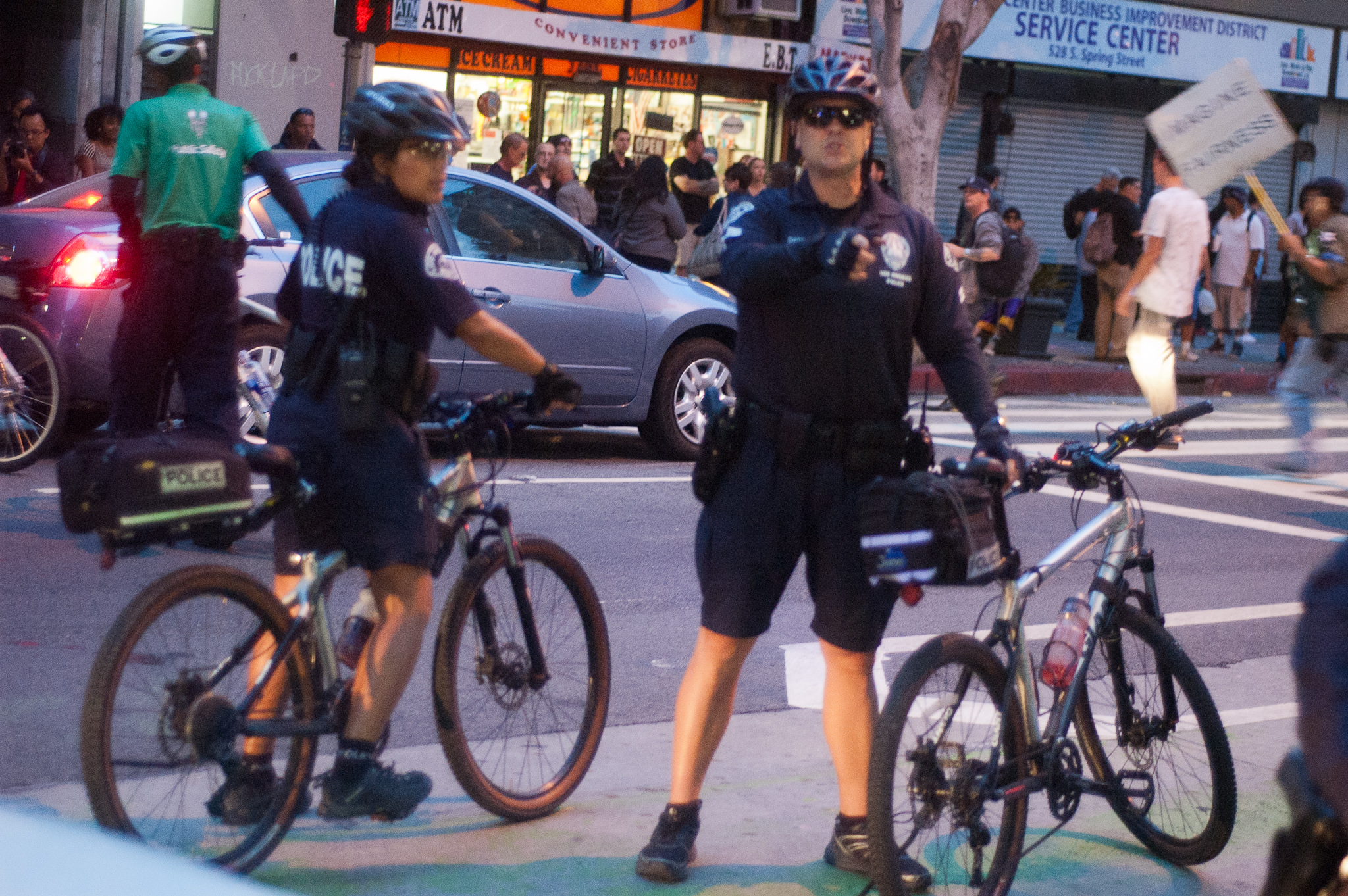Two Lapd Bike Cops With A Security Guard In The Background