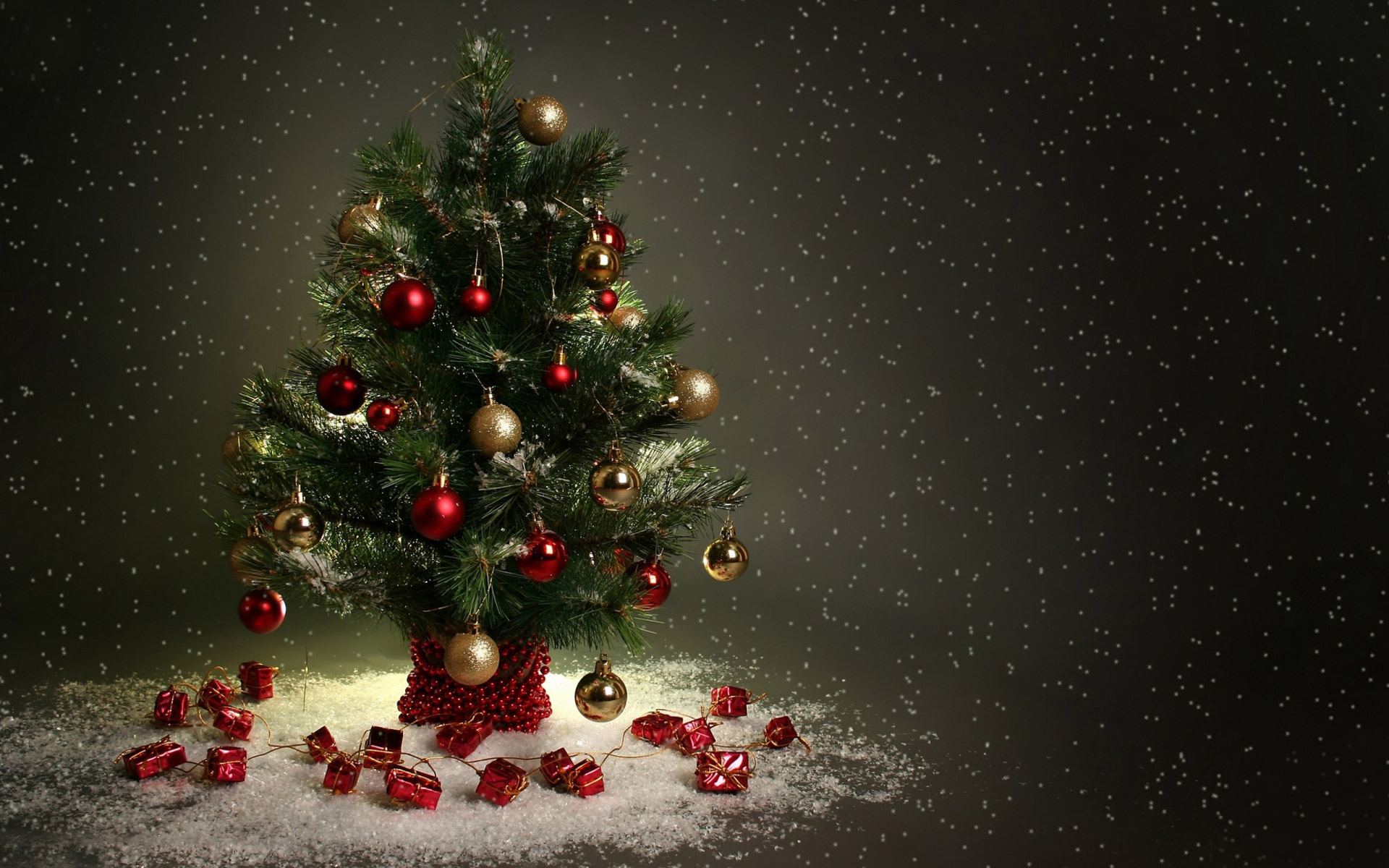 Christmas tree with red and gold ornaments, on a snowy surface, against a dark background with falling snow