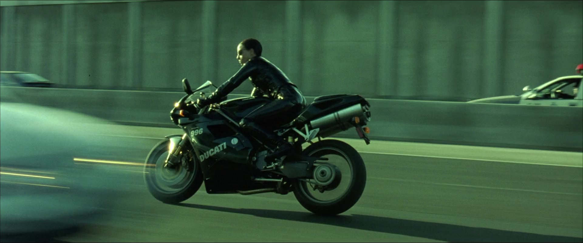 A woman in black leather suit riding a Ducati 996 motorcycle on a highway
