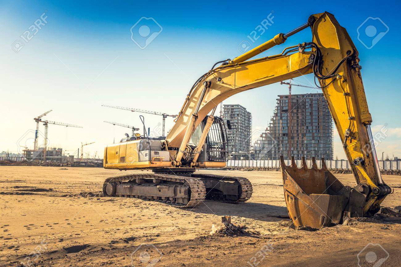 Excavator On Construction Site With Bulldings In Background