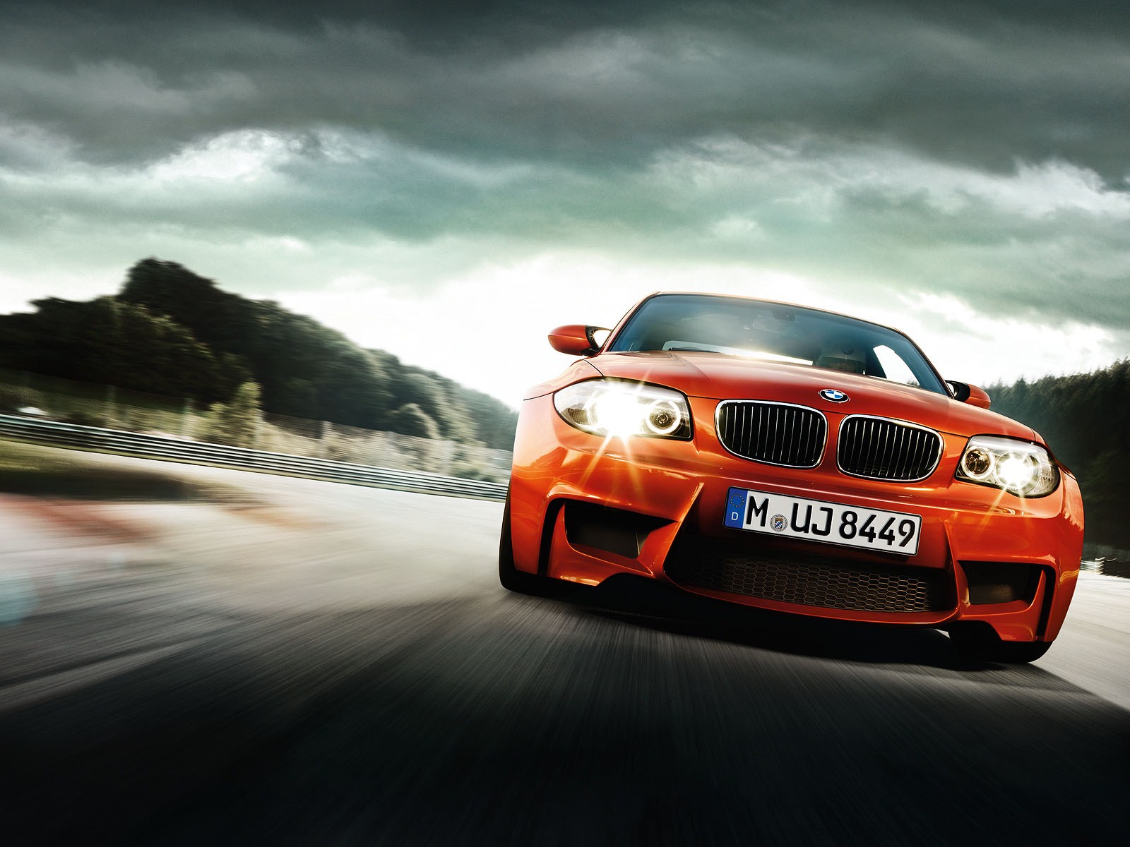 Orange BMW 1 Series M Coupe driving on a racetrack