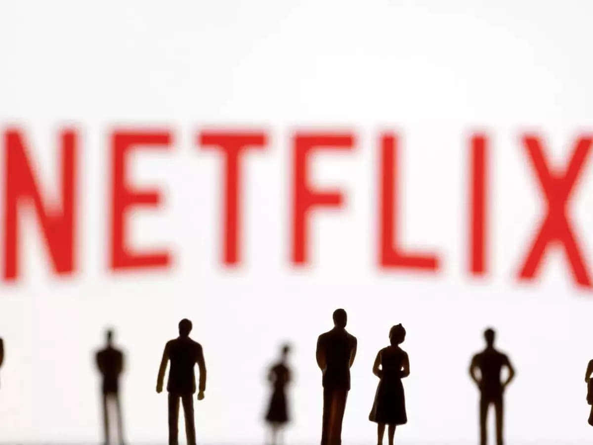 Silhouettes of people standing against a backdrop with the Netflix logo