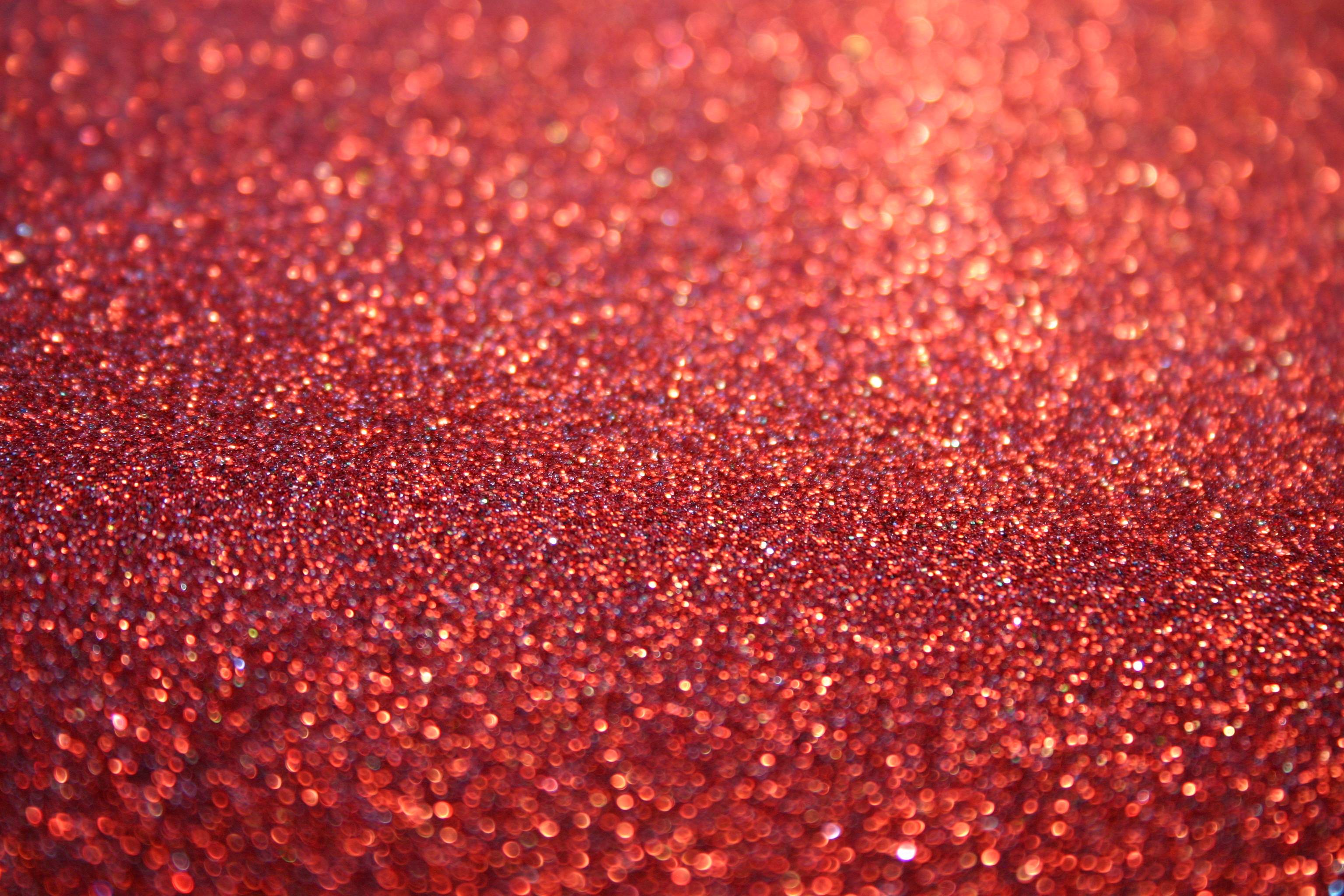 Close-up of a surface covered in red glitter, creating a sparkling, textured effect
