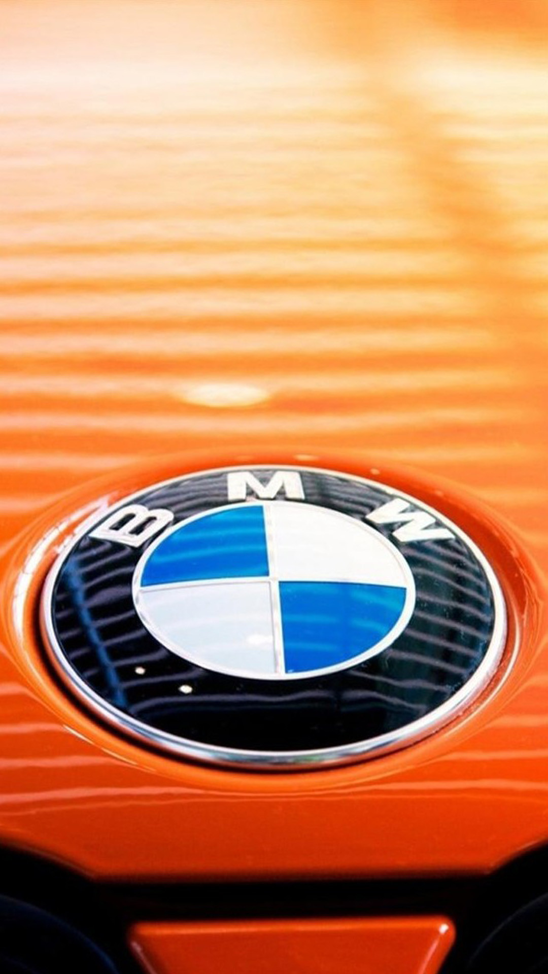 Close-up of a BMW logo on an orange car hood, highlighting the brand's iconic emblem